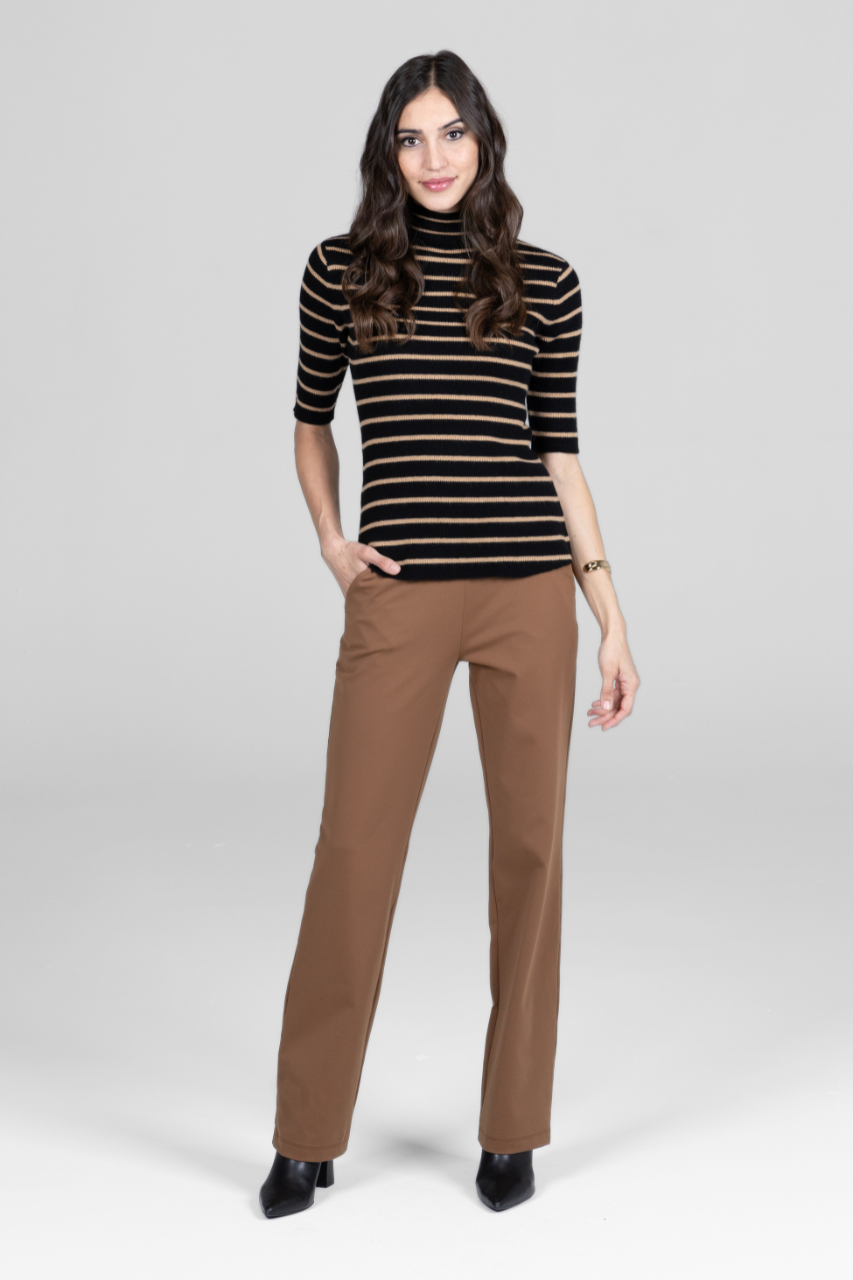 Woman wearing a black and gold striped sweater with brown pants on a white background