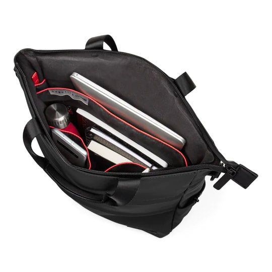 Black backpack with red interior compartments containing silver items on a white background