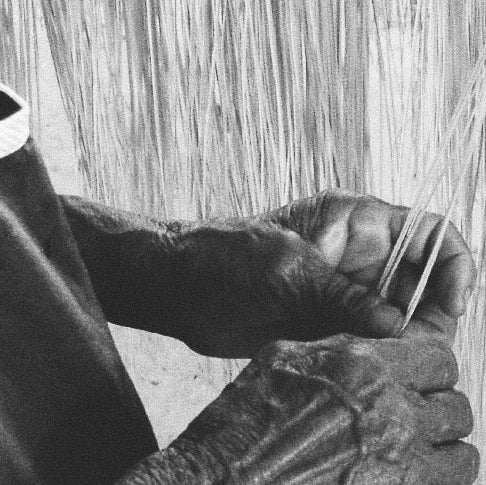 Close-up of hands weaving with a loom, black and white photo