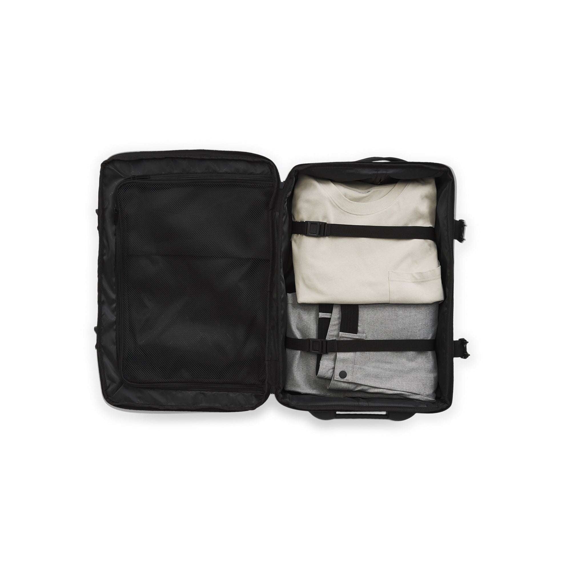 Black travel bag with clothes neatly packed inside on a white background