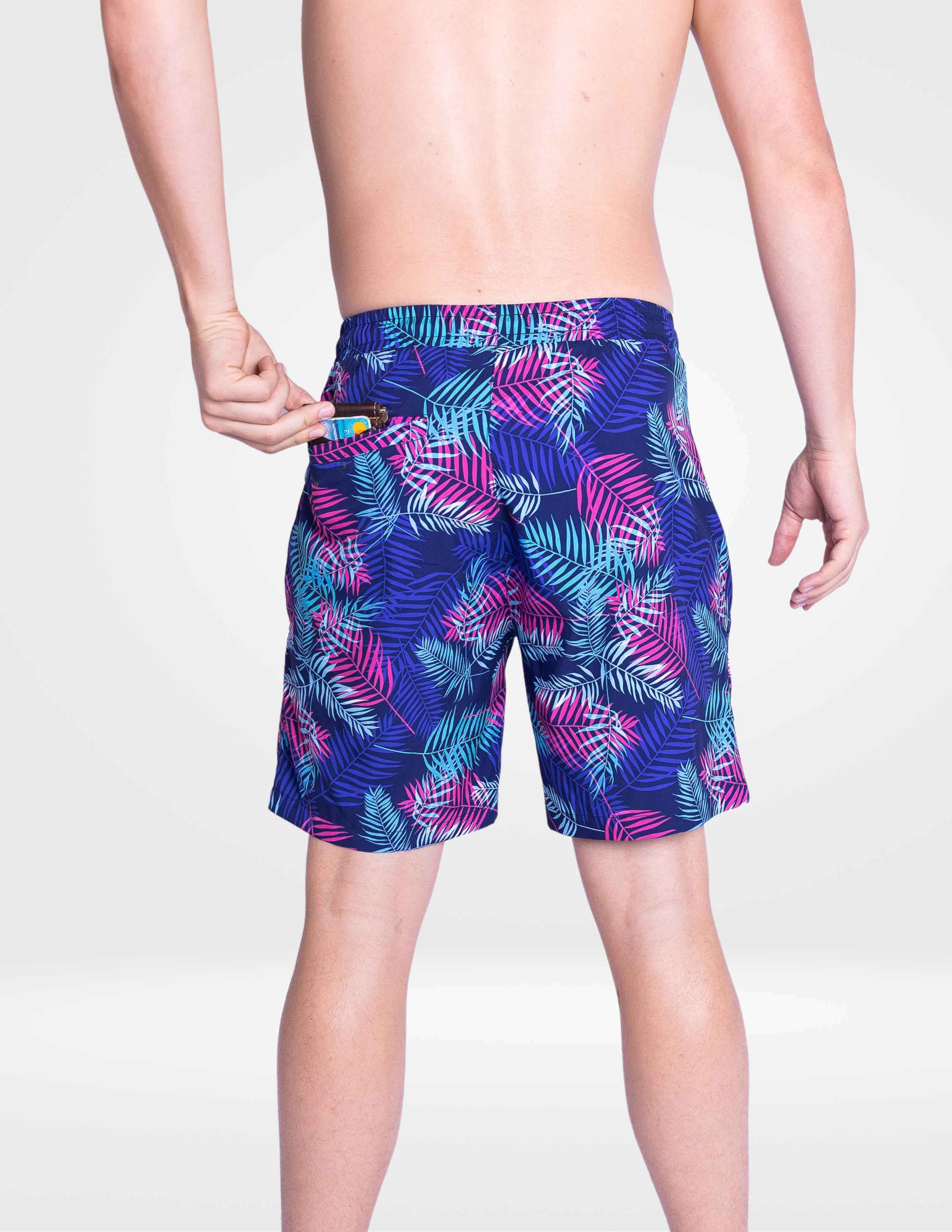 Person wearing colorful tropical leaf patterned shorts on a white background