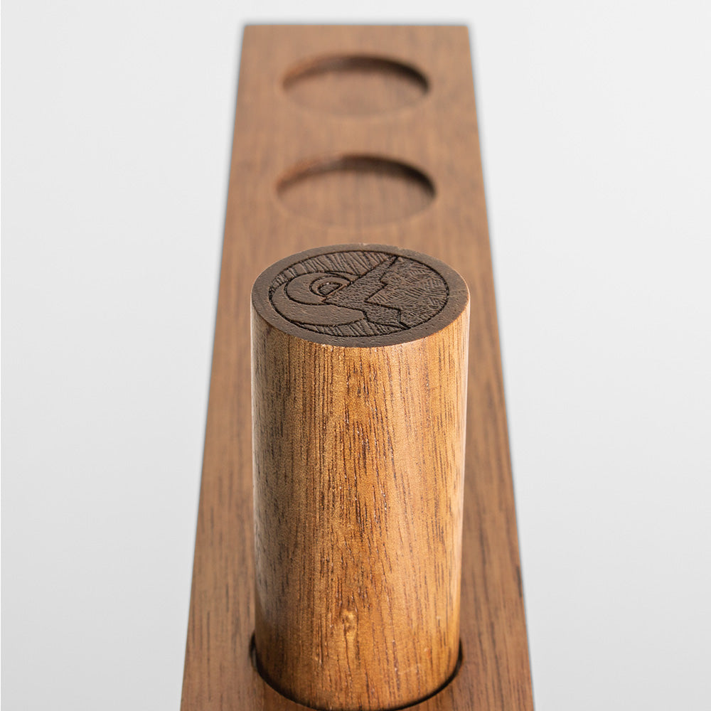 Wooden drink coaster with cylindrical holder on a plain background