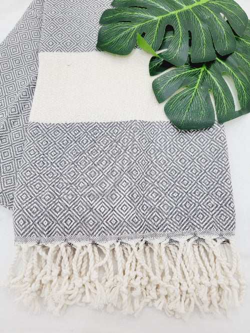 Gray and white patterned towel with tassels on a white background