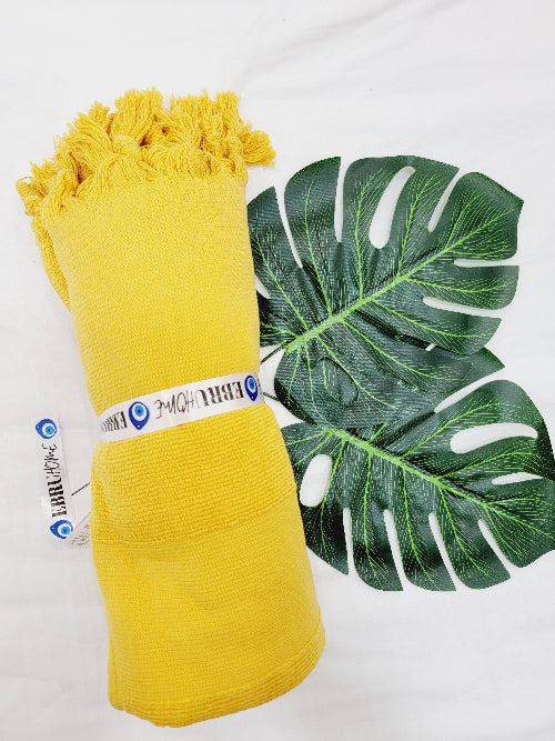 Yellow yarn skein with a green leaf on a white background