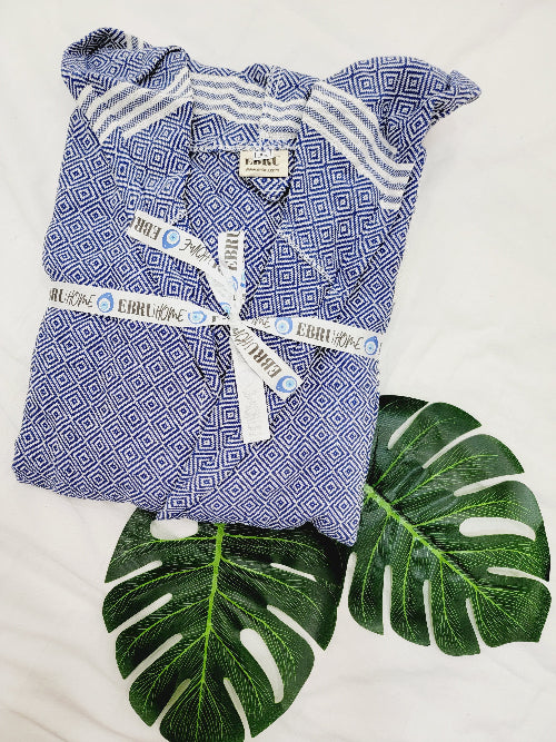 Blue patterned baby outfit with white stripes on a white background with green leaves.