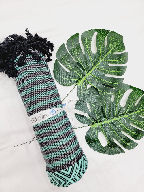Striped sock with black tassels and green leaves on a white background