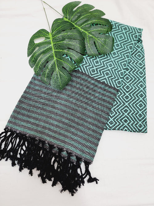 Green and black striped towel with tassels on a white background