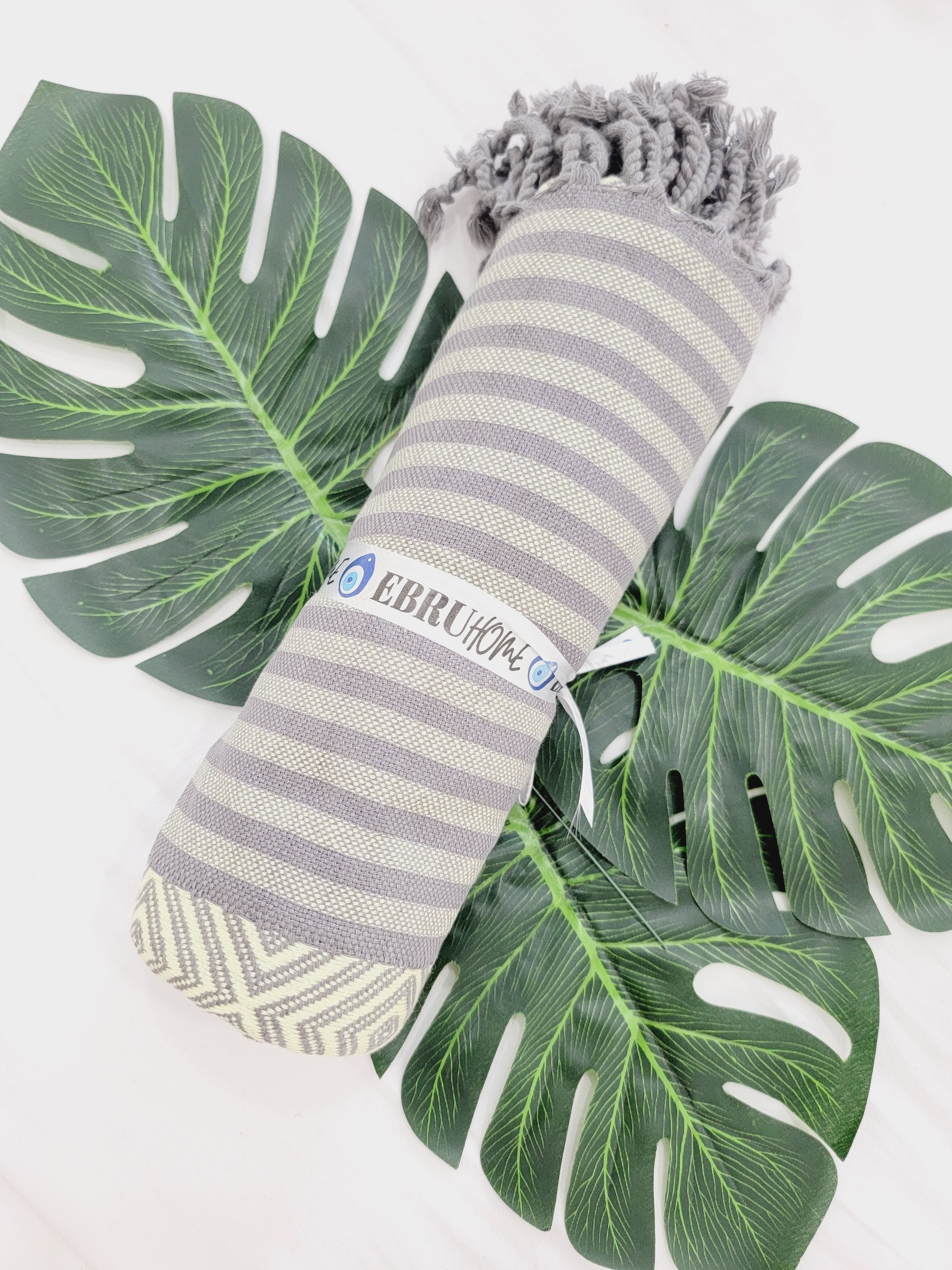 Striped towel with tassels on a white background with green leaves