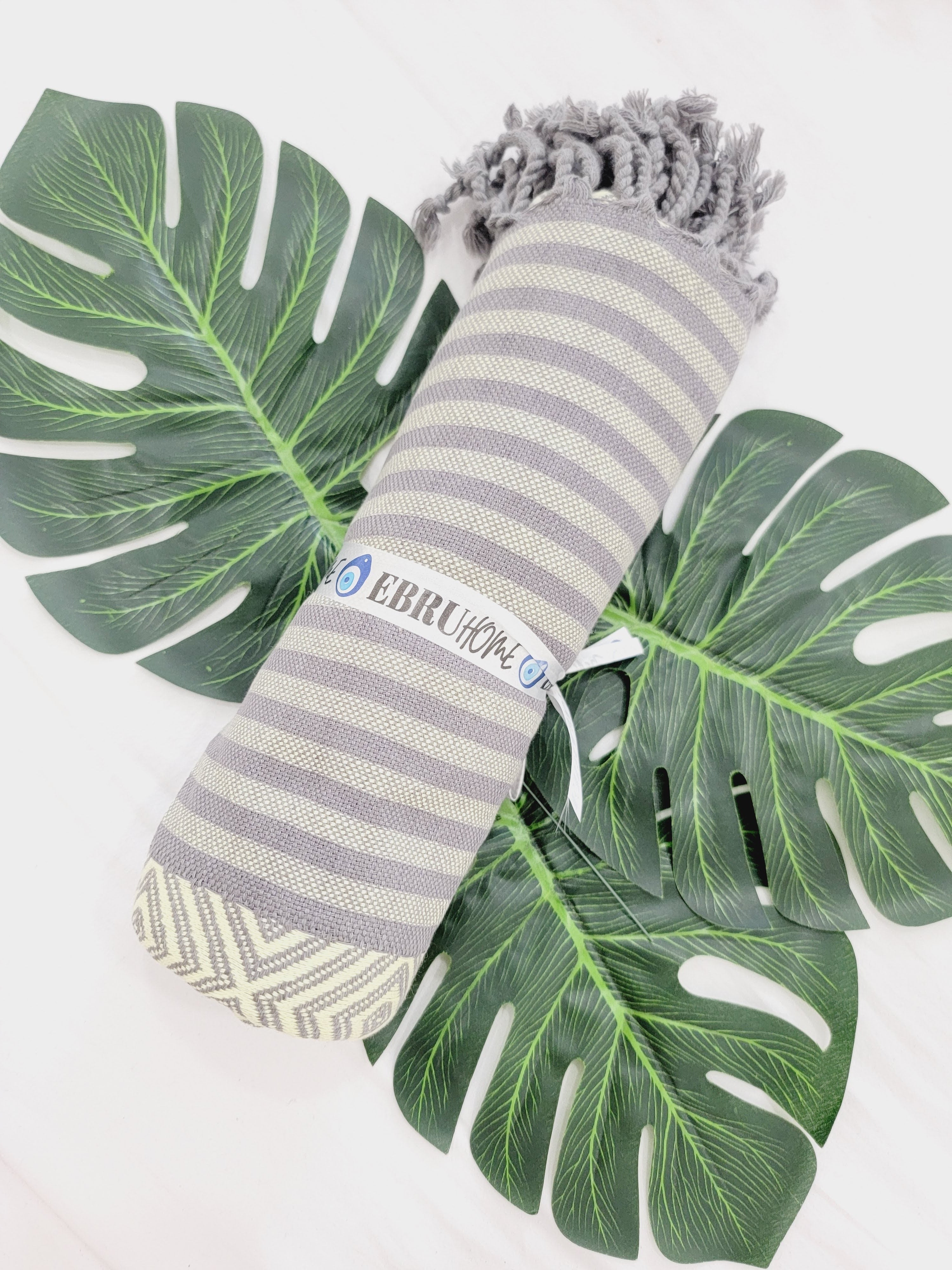 Striped towel with a brand logo on a white background with green leaves