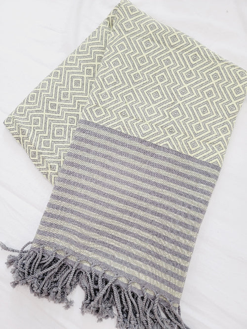 Two patterned towels, one green with geometric design and the other gray with stripes, on a white background.