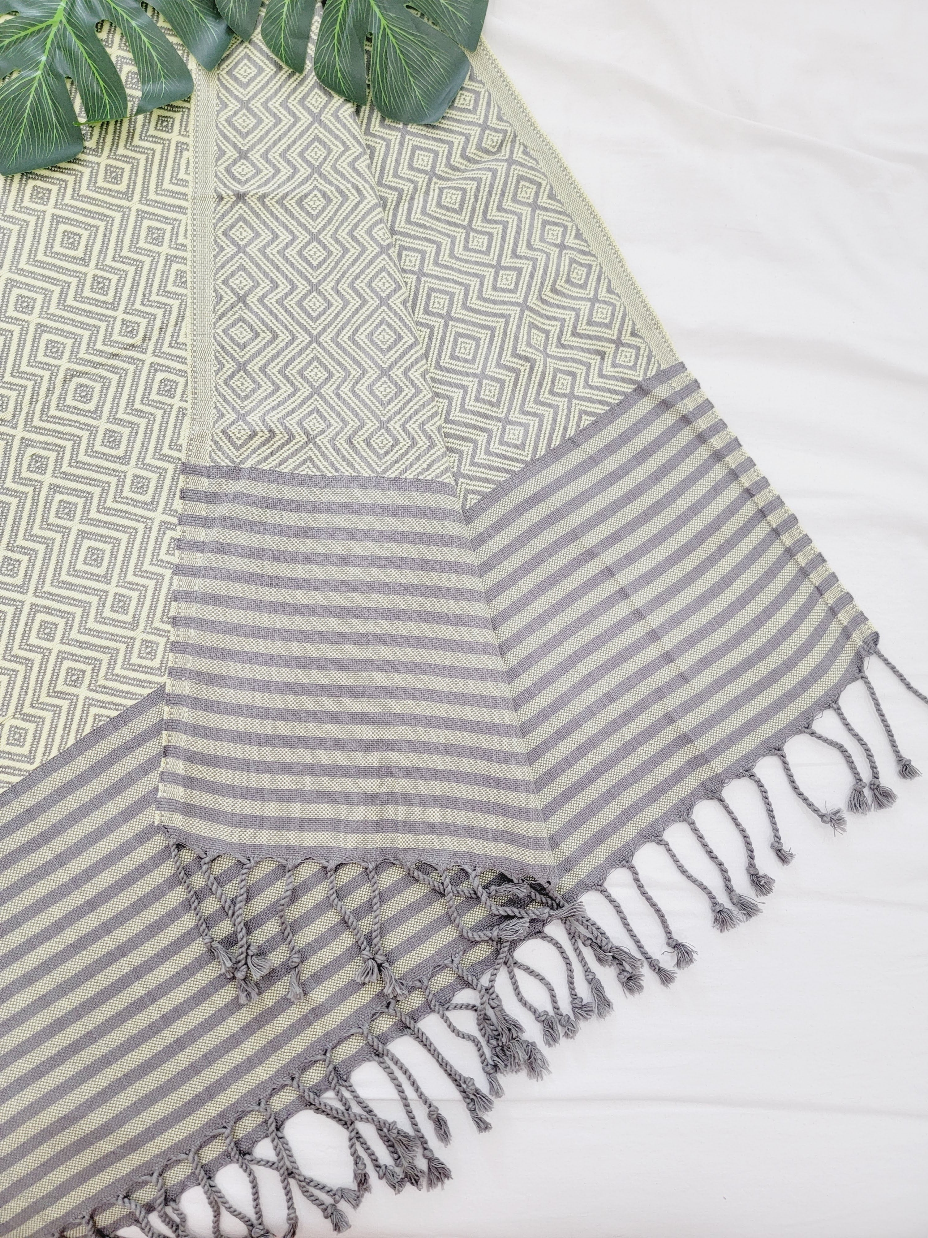 Gray striped towel with tassels on a patterned surface