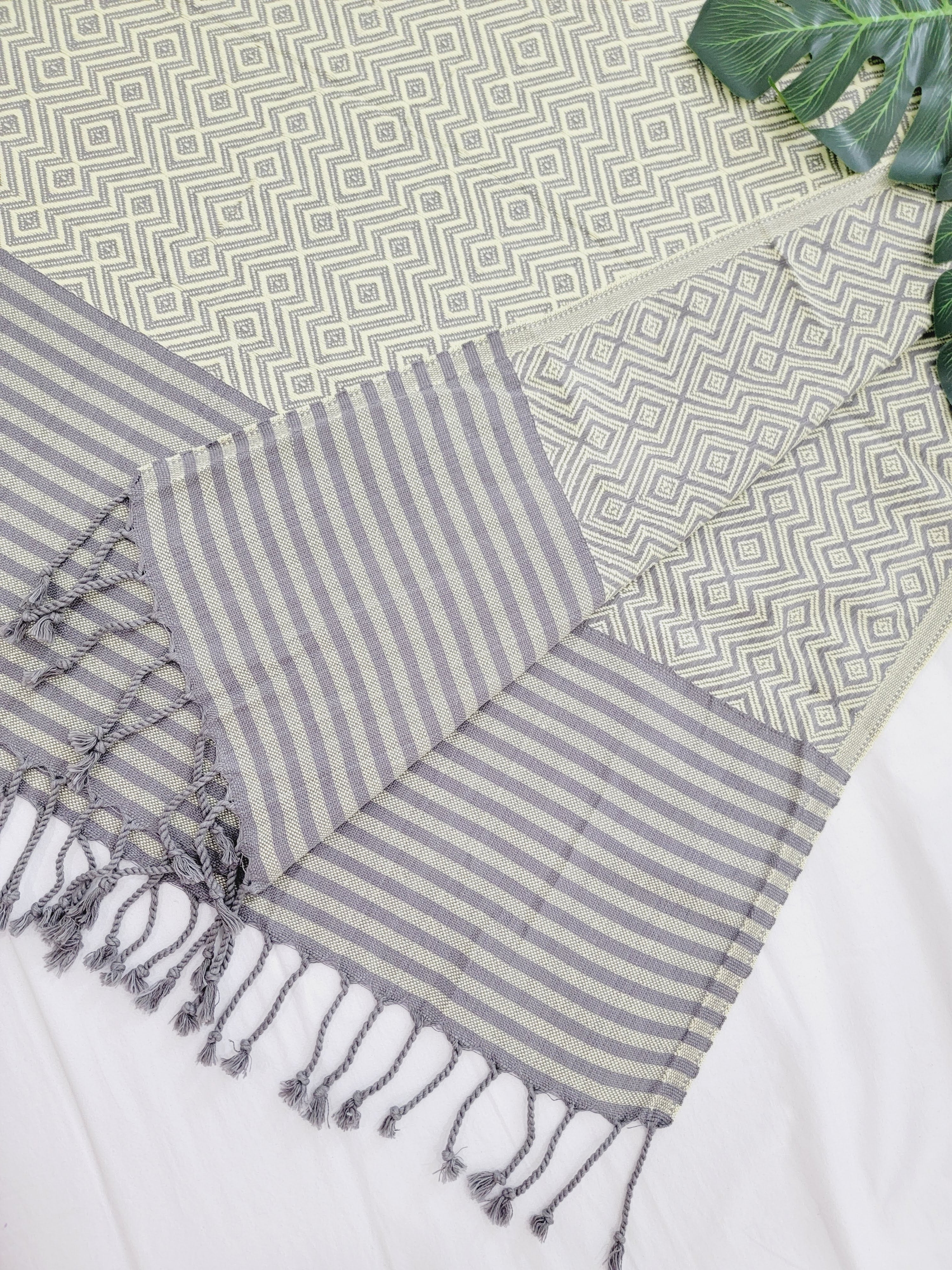 Striped towel with tassels on a geometric patterned surface