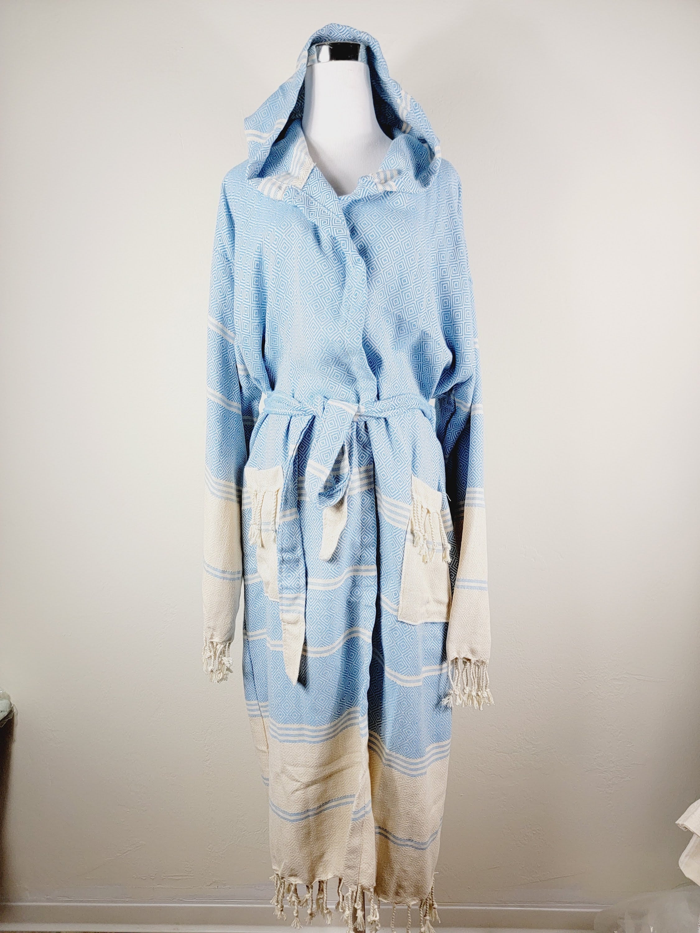 Light blue and beige robe with fringe on a mannequin against a plain background