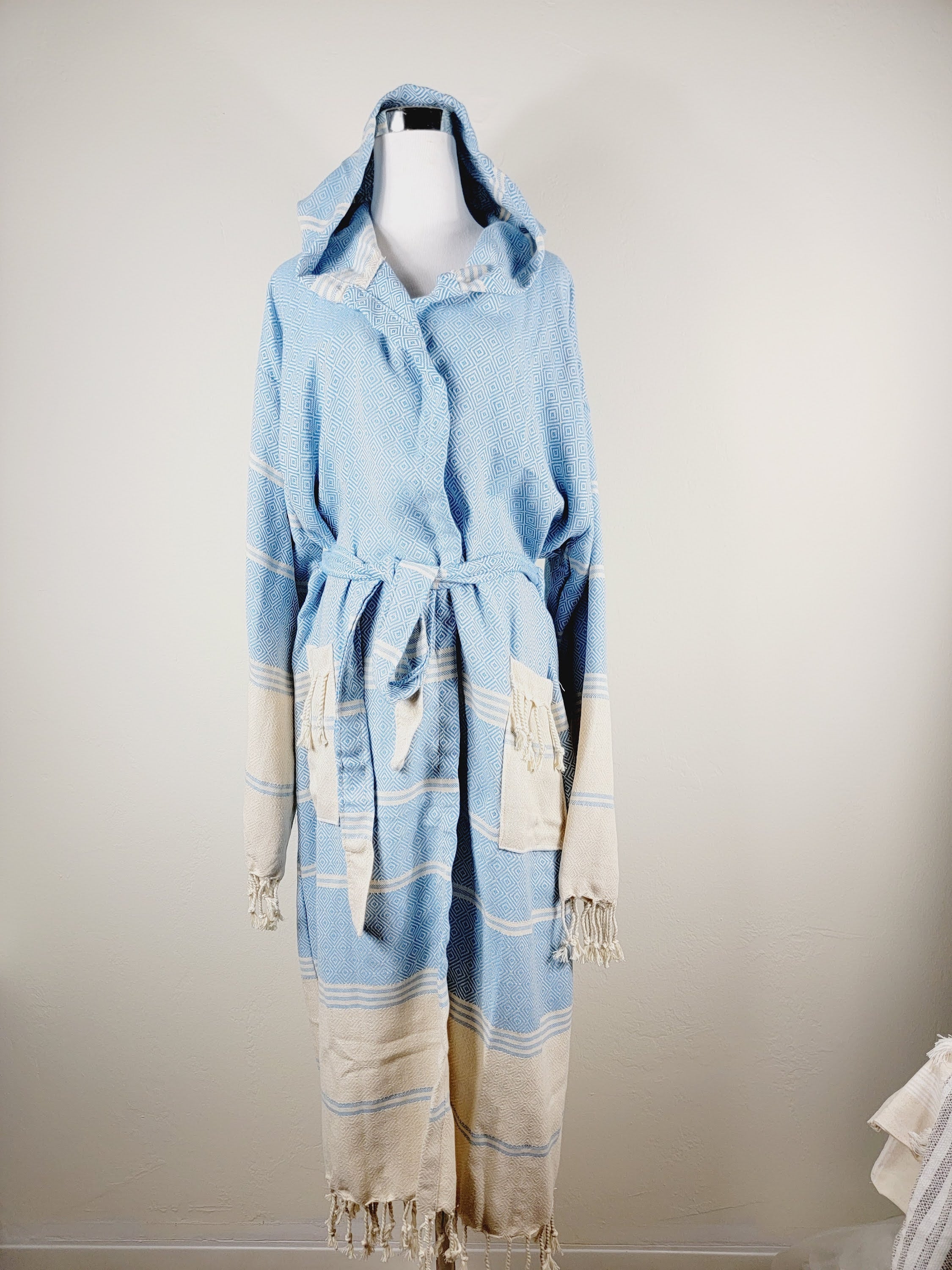Light blue and beige robe with tassels on a mannequin against a plain background