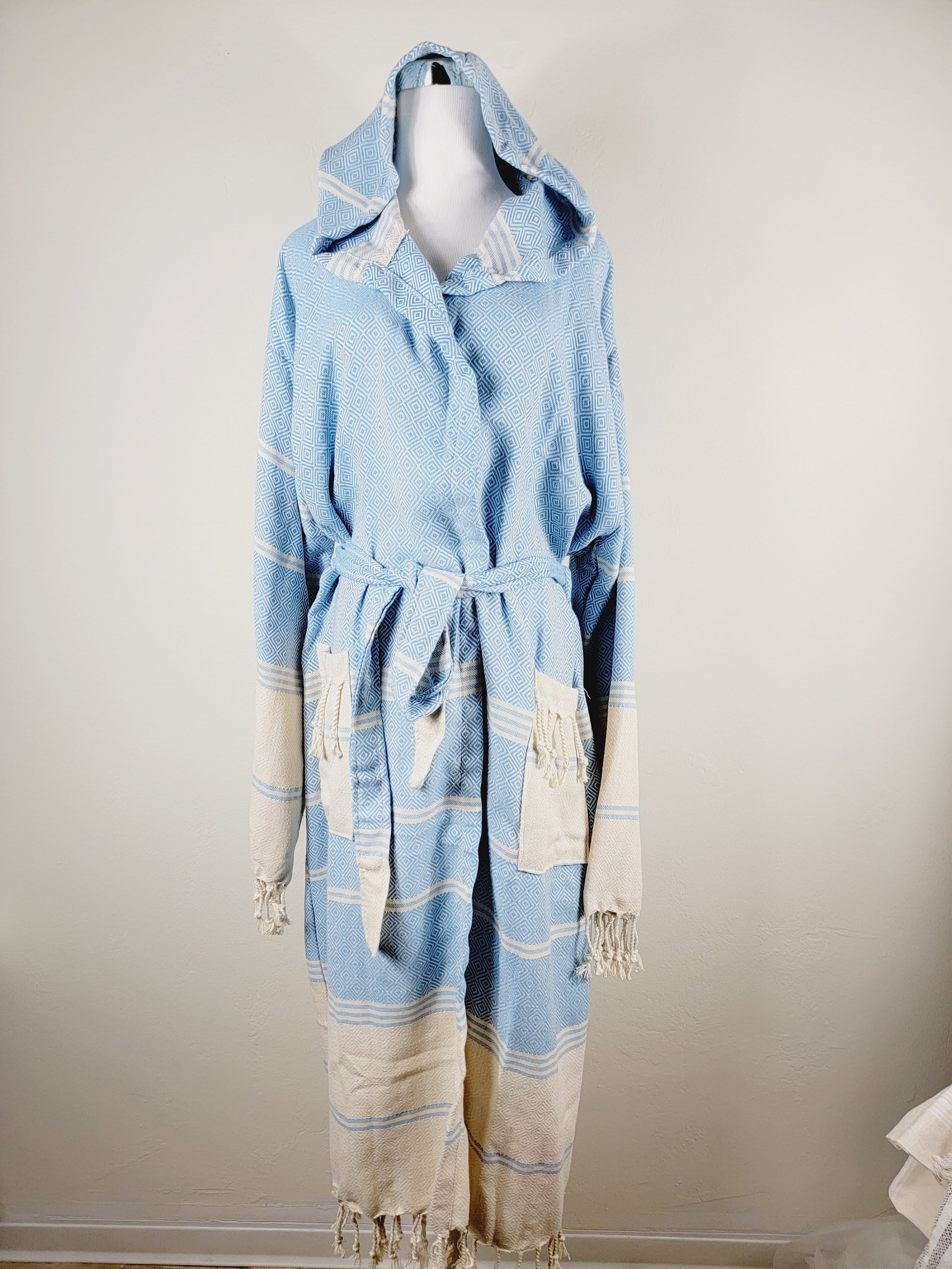 Light blue and beige robe with hood on a mannequin against a plain background