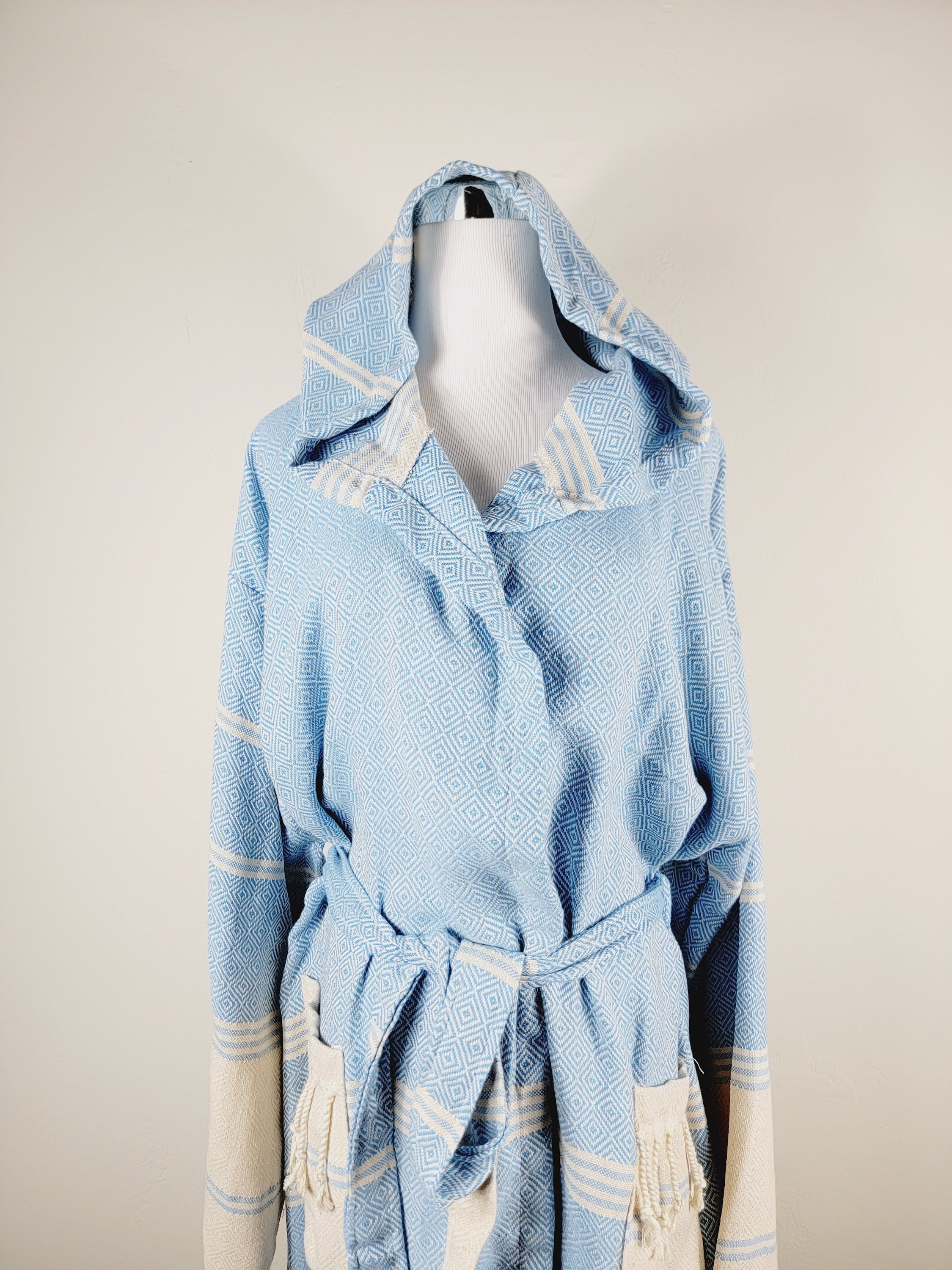Light blue hooded garment on a mannequin against a beige background