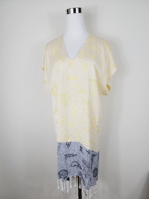 Mannequin wearing a yellow and gray patterned scarf with fringe on a white background