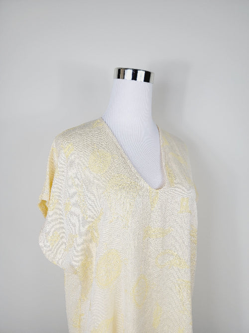 Mannequin wearing a yellow and white patterned top against a gray background