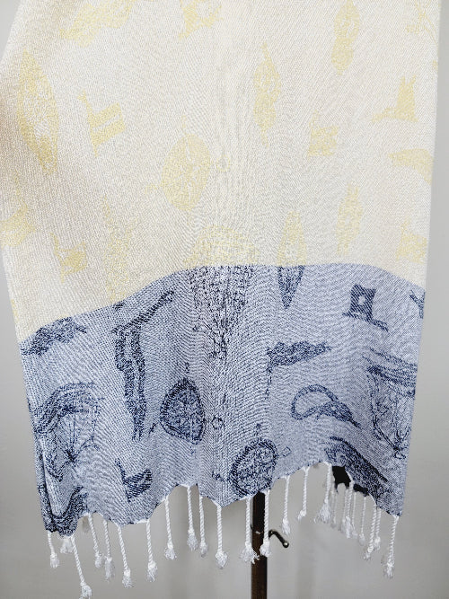 Shawl with blue pattern and white fringe on a mannequin against a neutral background