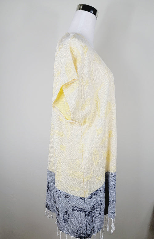Mannequin wearing a yellow and gray scarf with fringe on a plain background