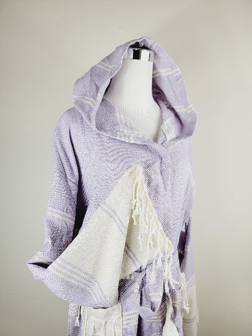 Mannequin wearing a light purple and white striped towel with fringes on a neutral background