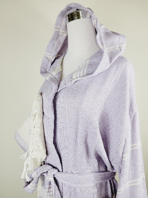 White and gray patterned robe with tassels on a mannequin against a light background