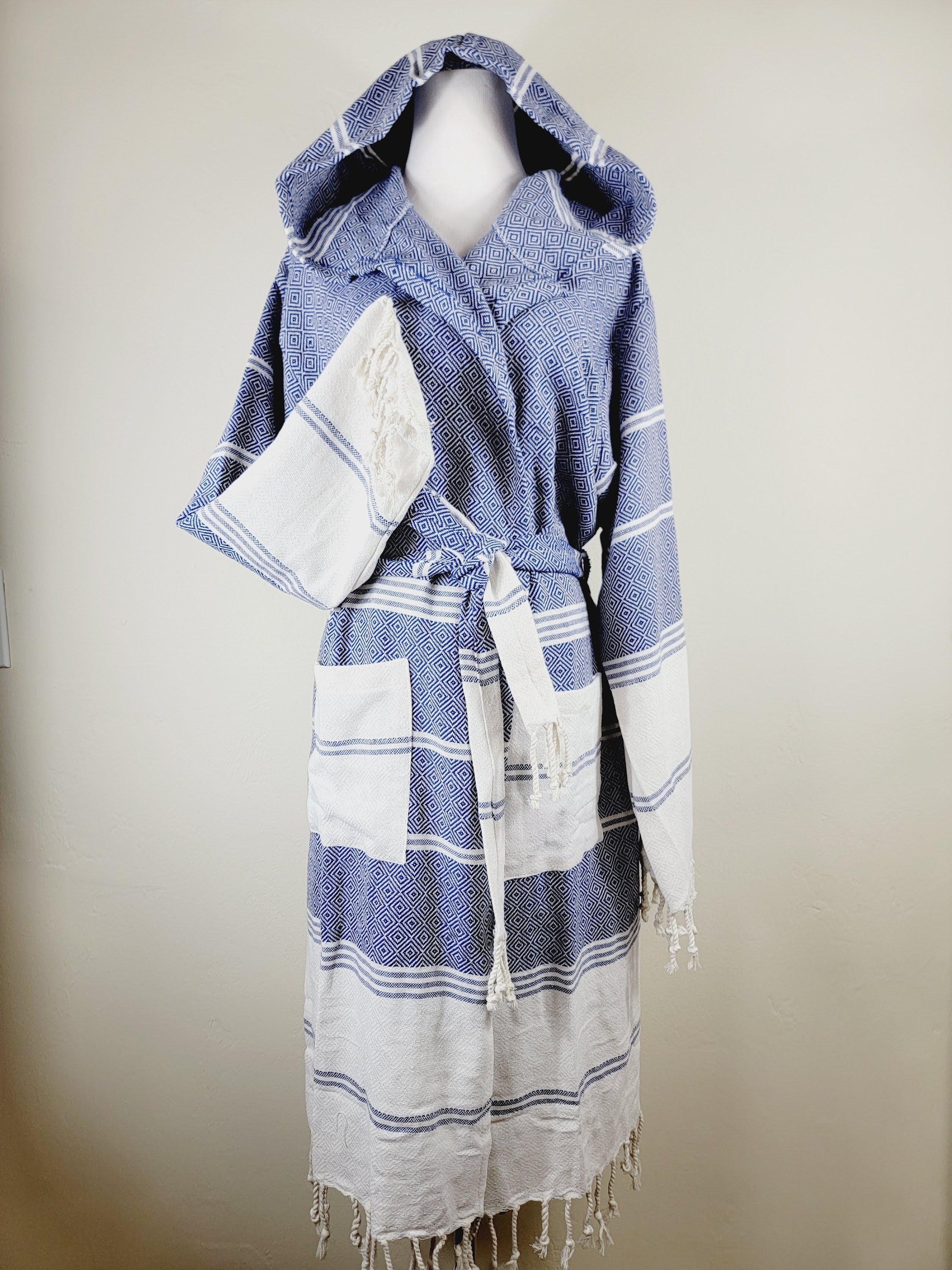 Blue and white striped robe with hood on a mannequin against a beige background