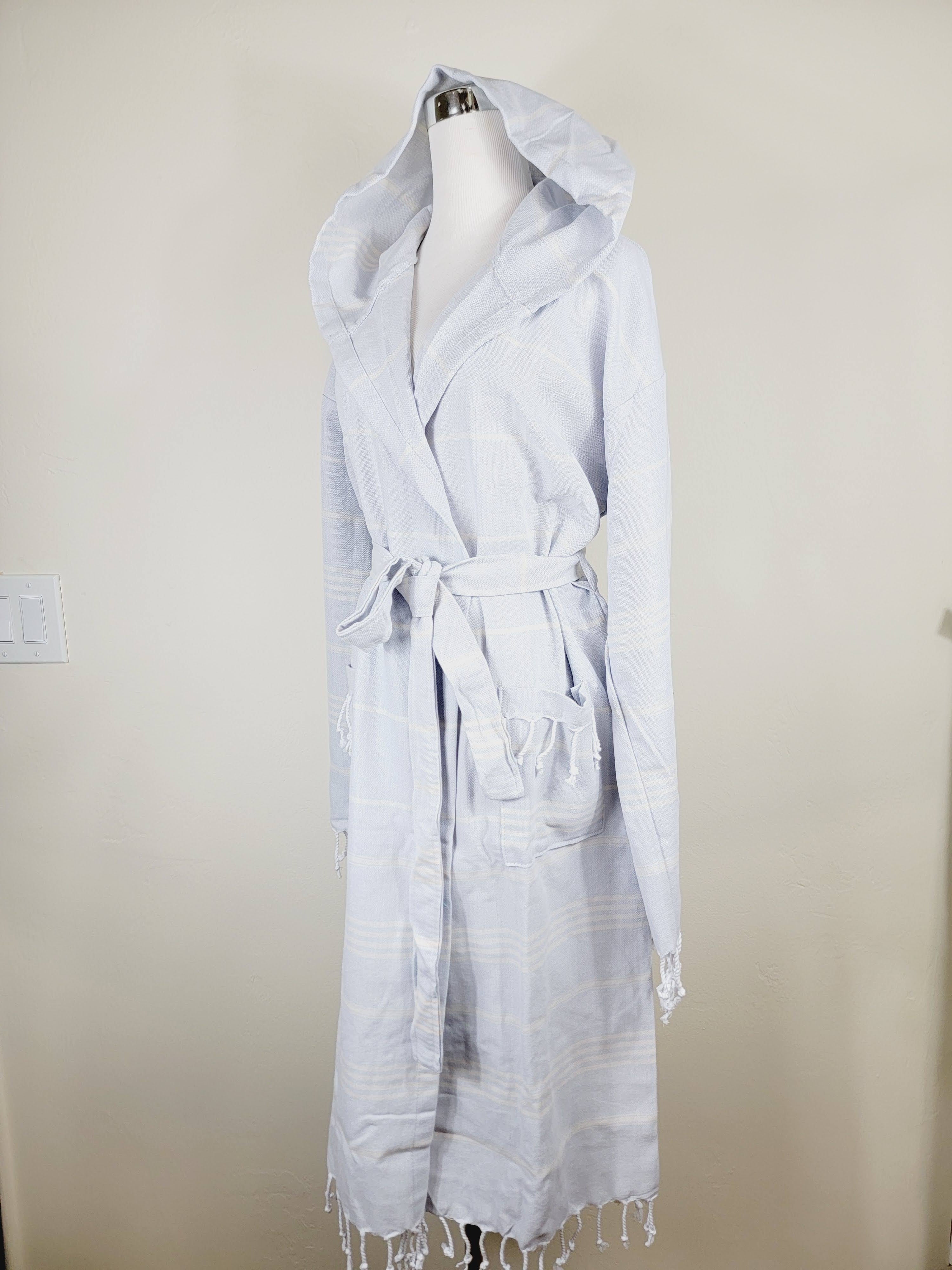Light blue hooded robe on a mannequin against a beige wall.