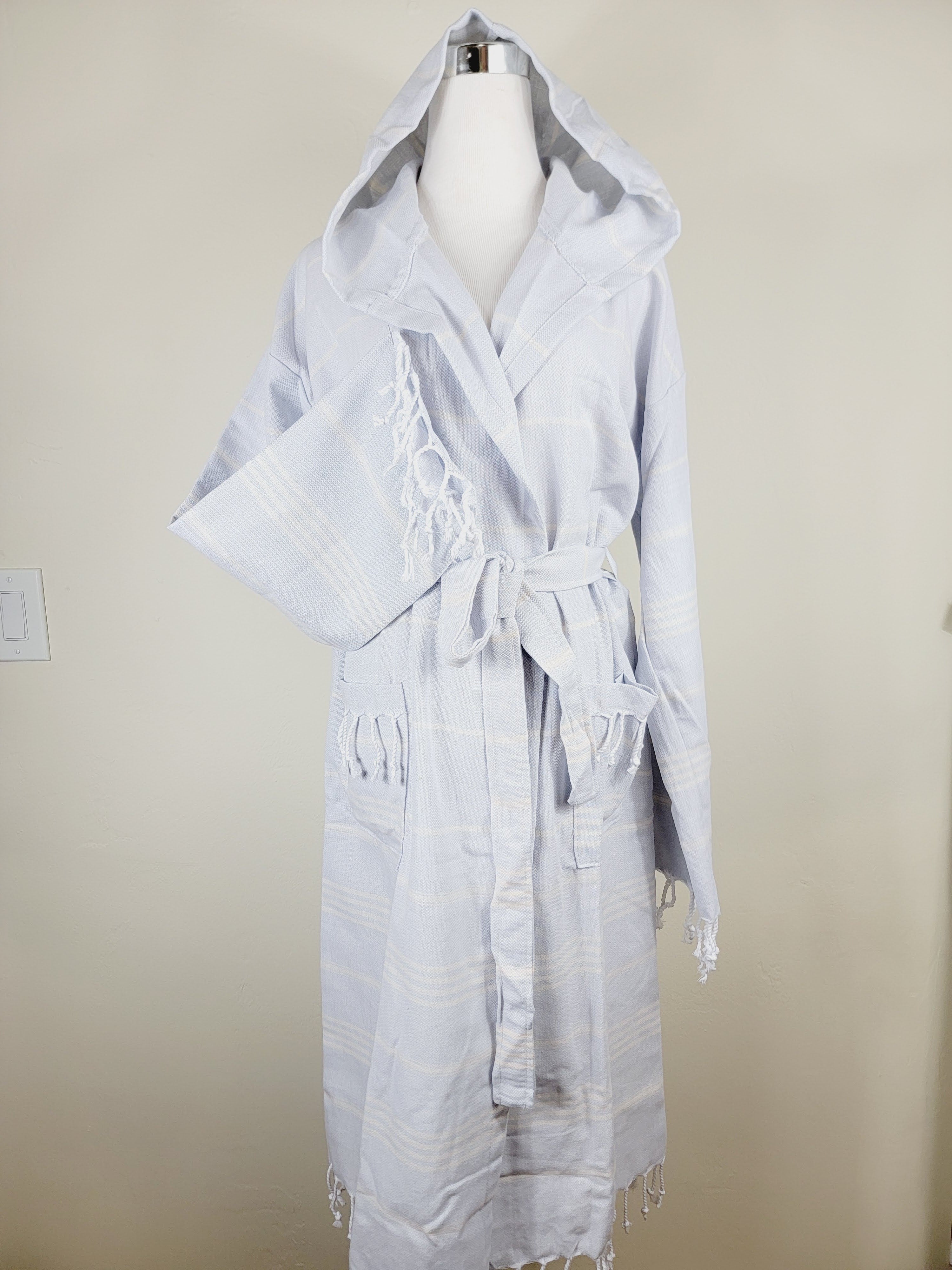 Light blue hooded robe on a mannequin against a beige wall.