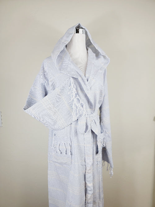 White hooded robe with fringe details on a mannequin against a beige background