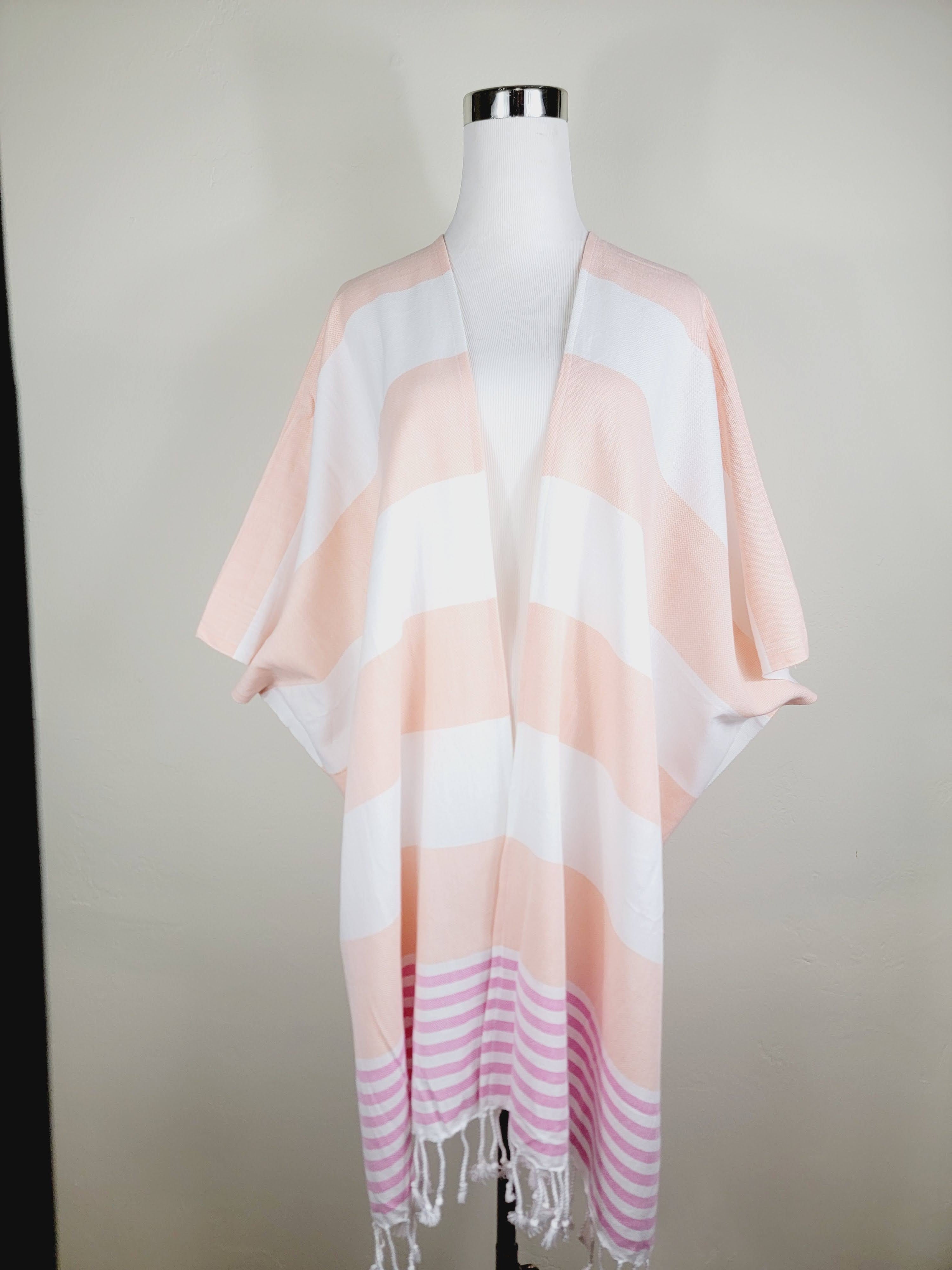 Mannequin wearing a pink and white striped kimono with fringe on a plain background