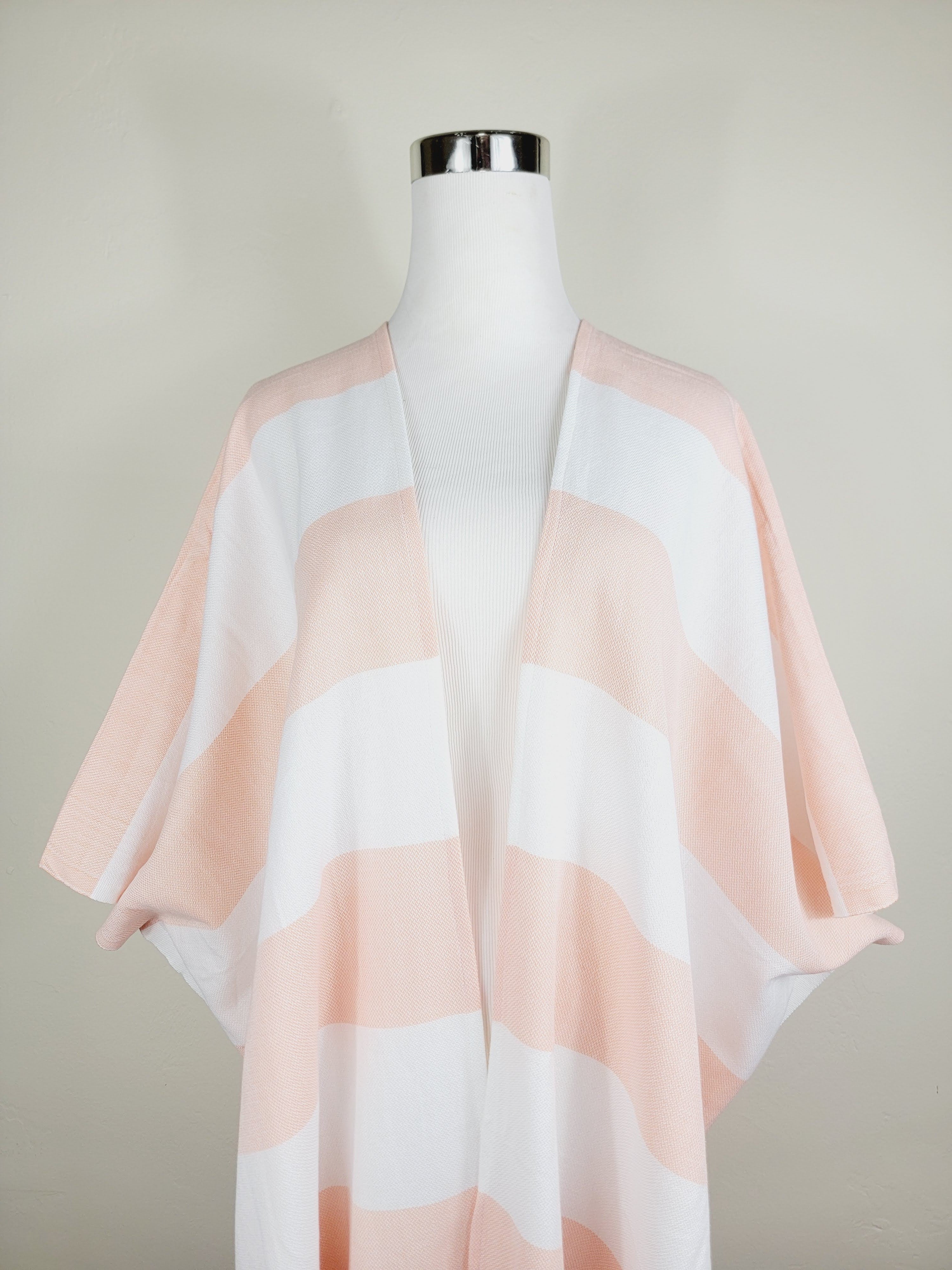 Mannequin wearing a light pink and white striped scarf against a plain background