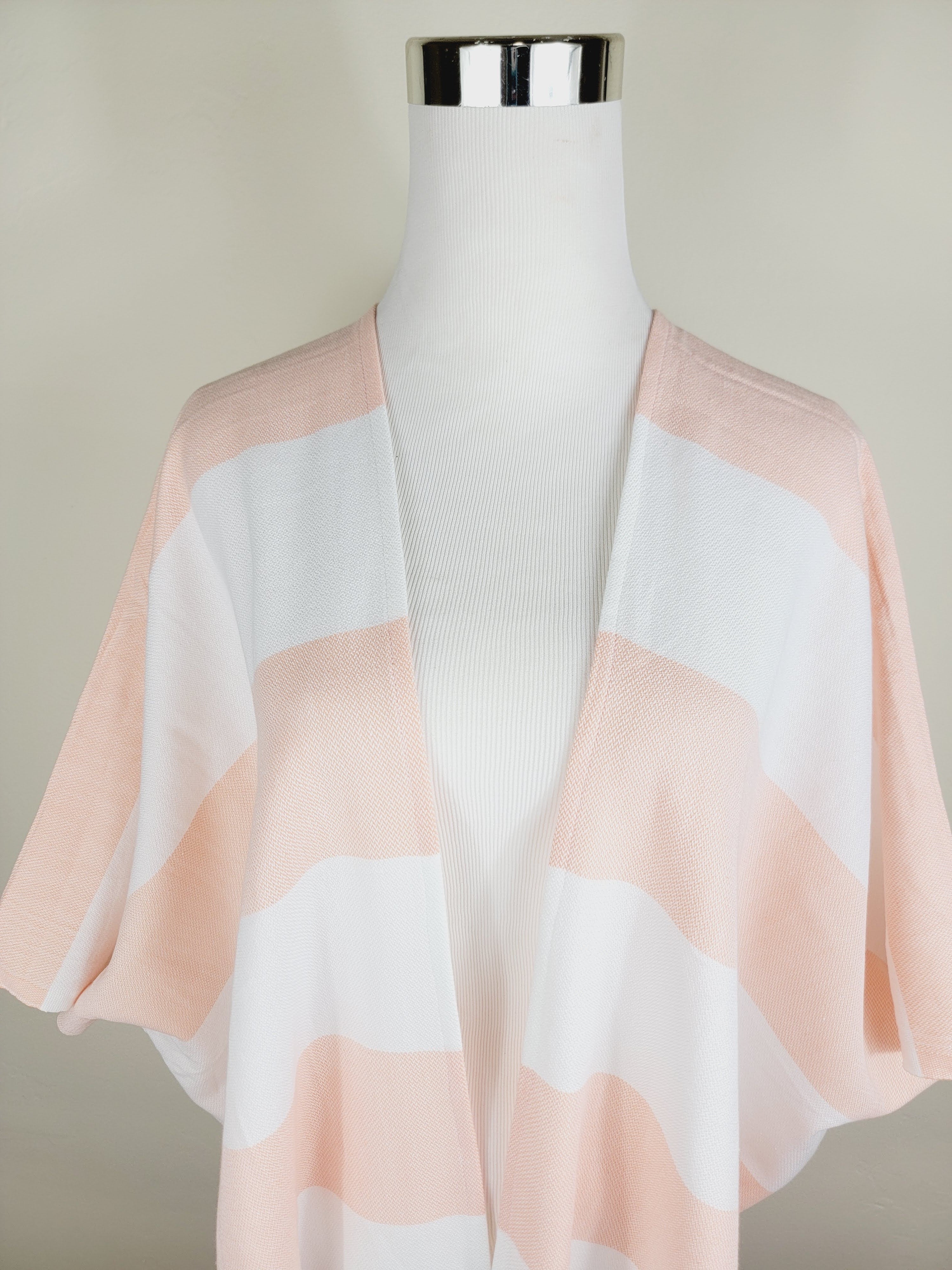 Pink and white striped scarf on a mannequin against a neutral background