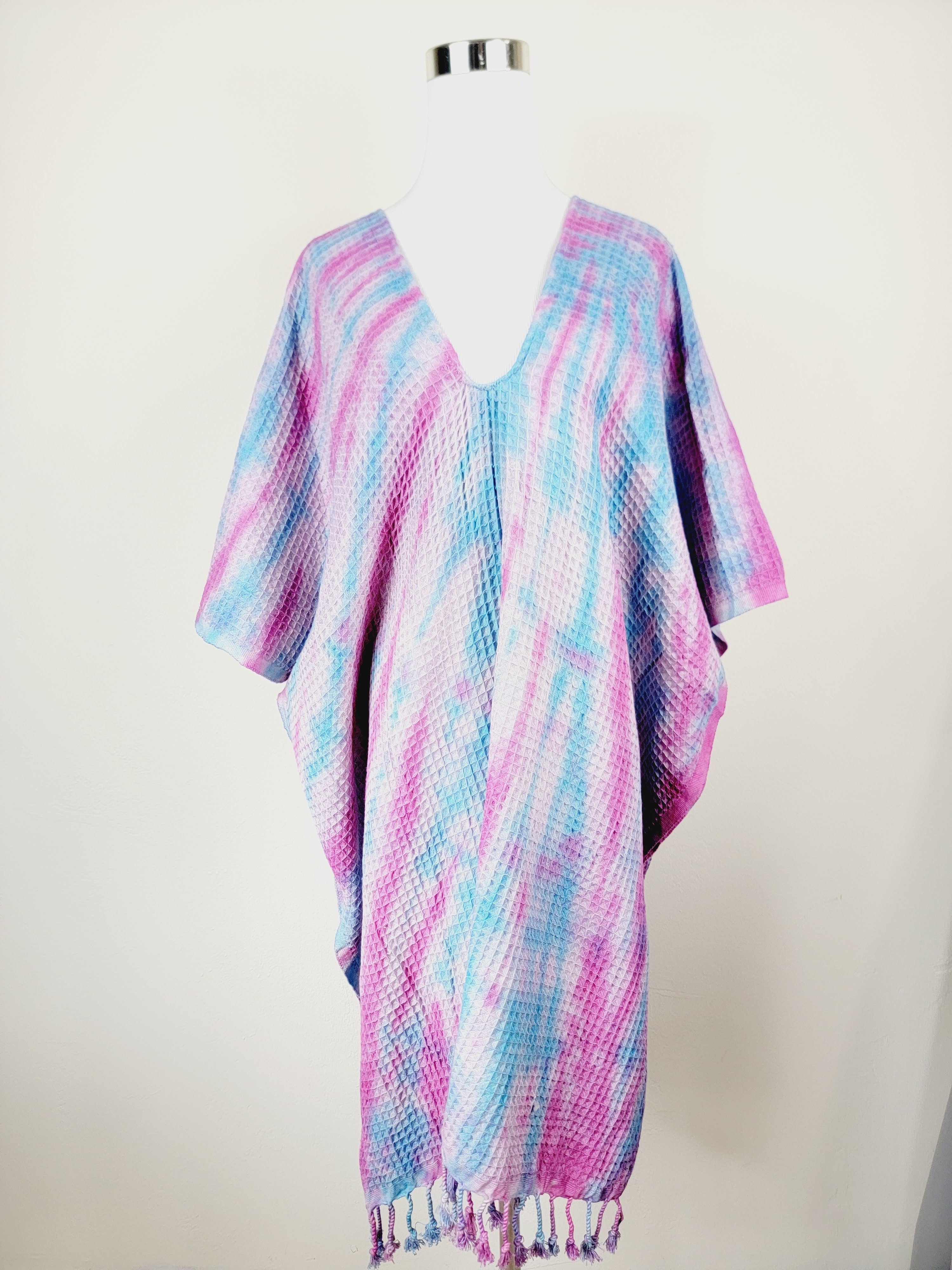 Colorful patterned poncho on a mannequin against a white background