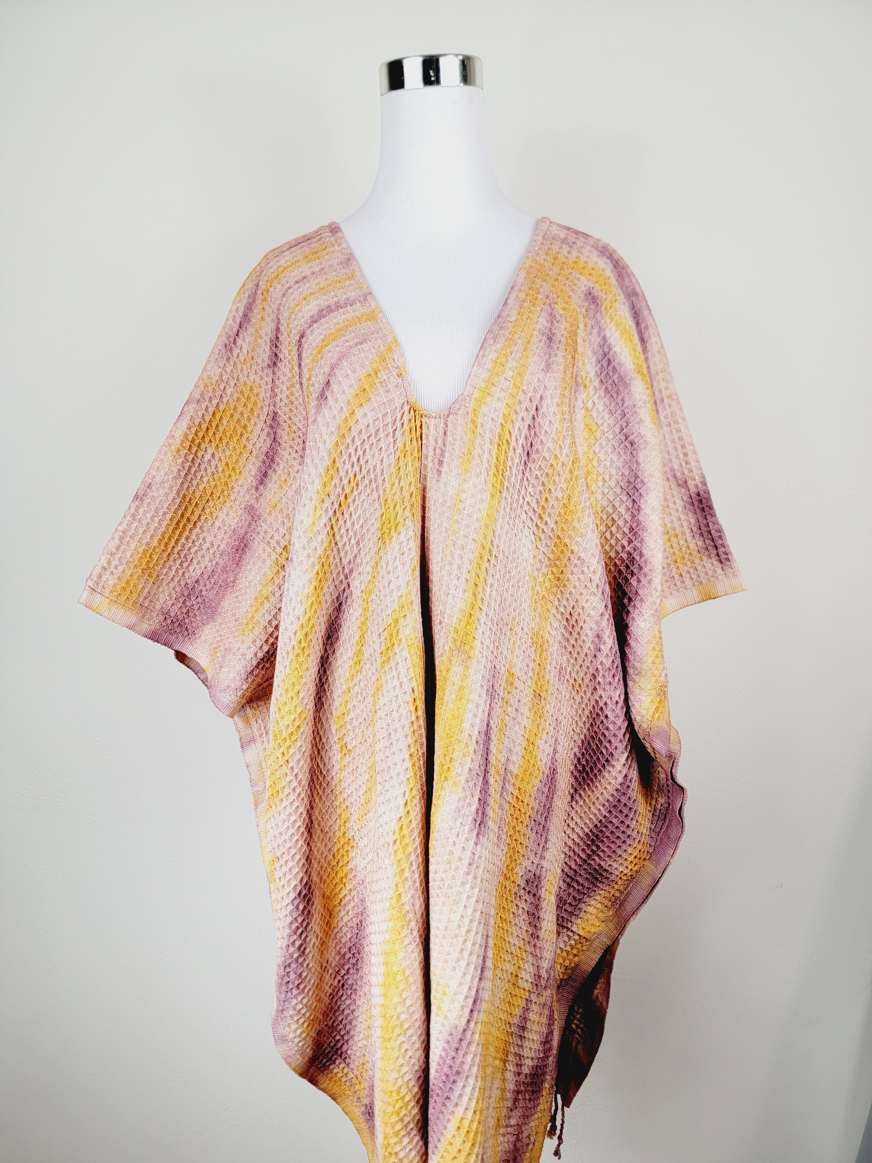 Colorful knitted poncho on a mannequin against a white background