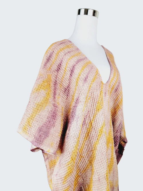 Mannequin wearing a pink and yellow patterned poncho against a plain background