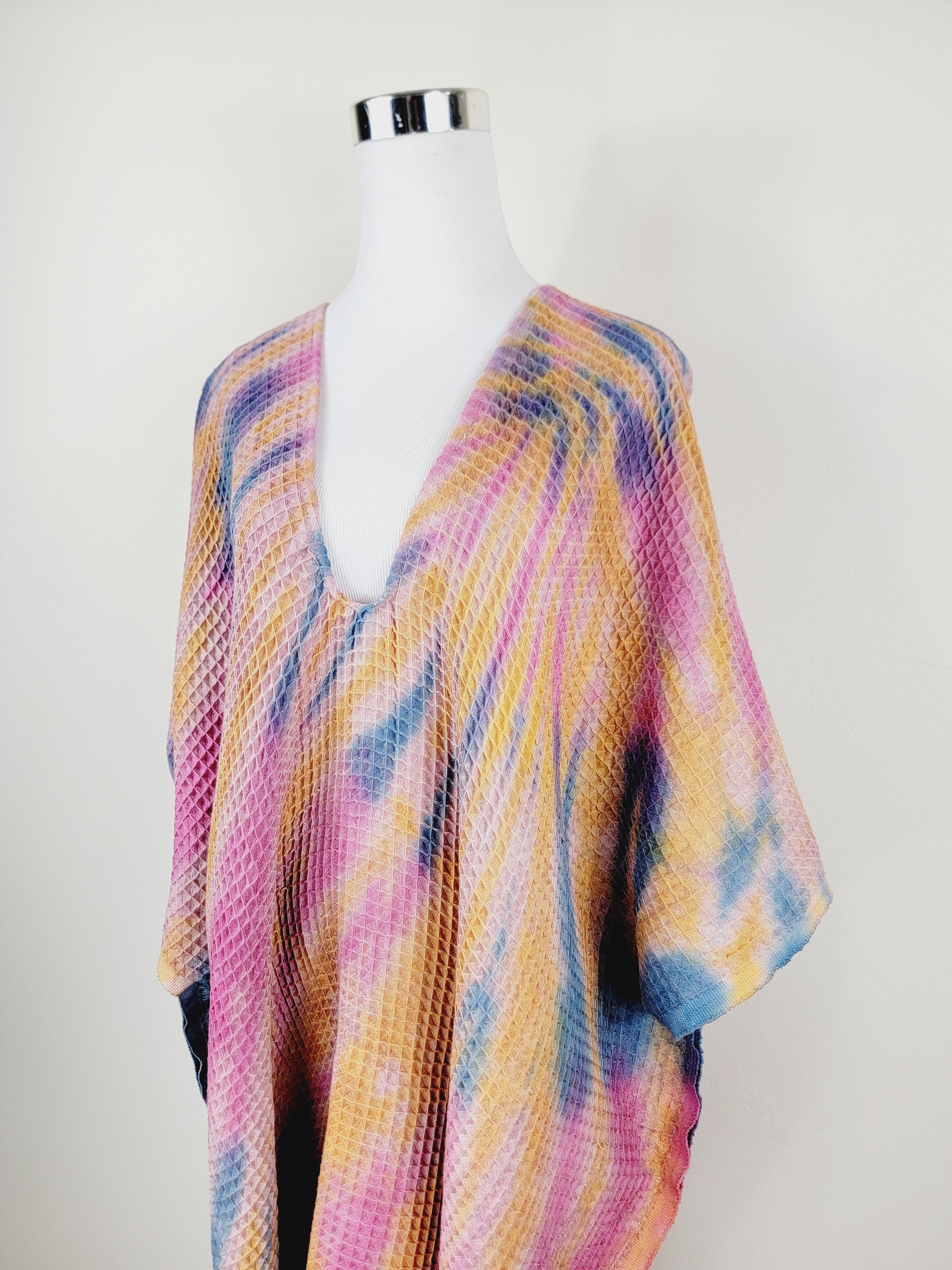 Colorful knitted poncho on a mannequin against a white background