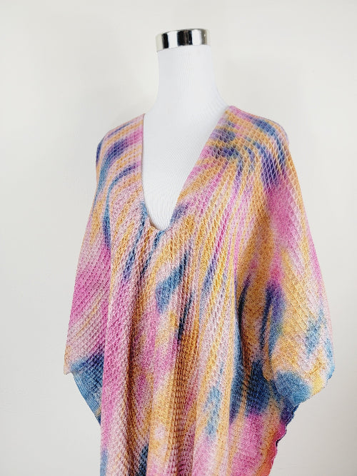 Multicolored knit poncho on a mannequin against a white background