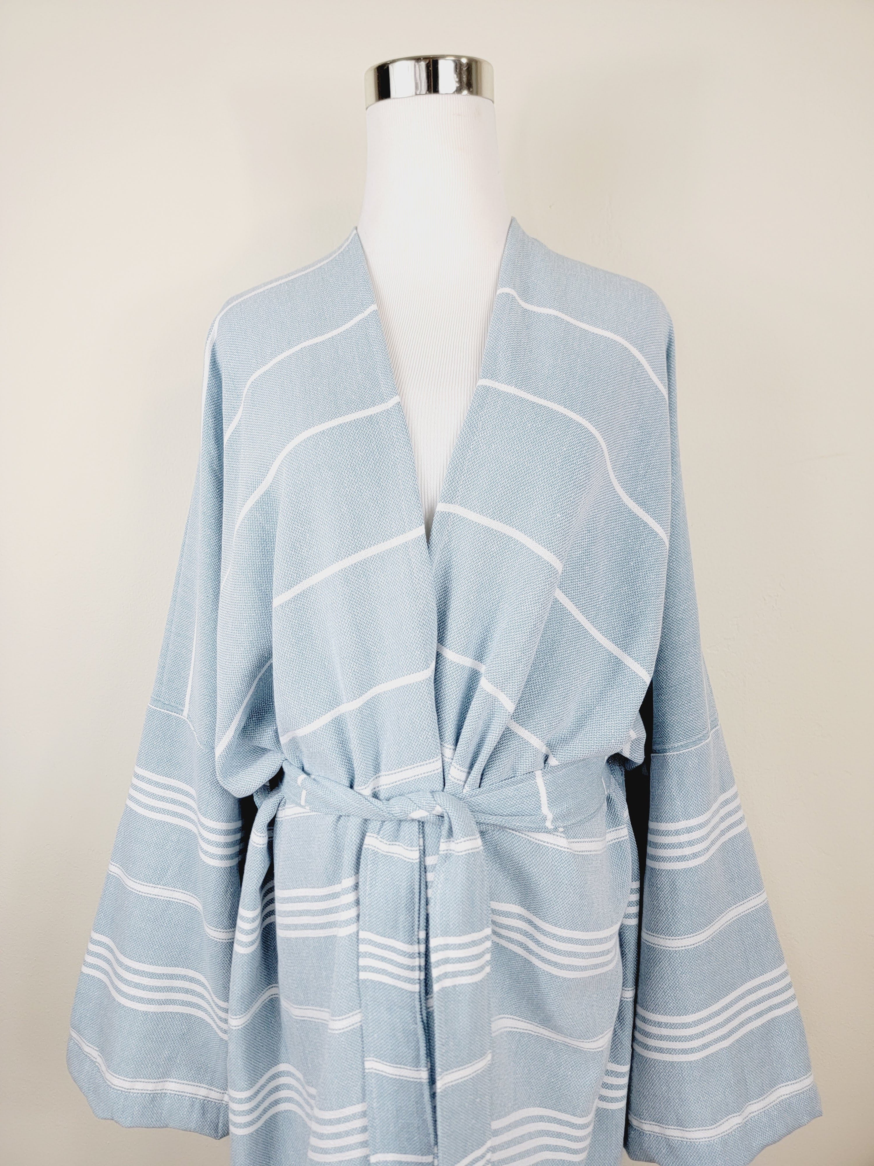 Light blue striped robe on a mannequin against a beige background