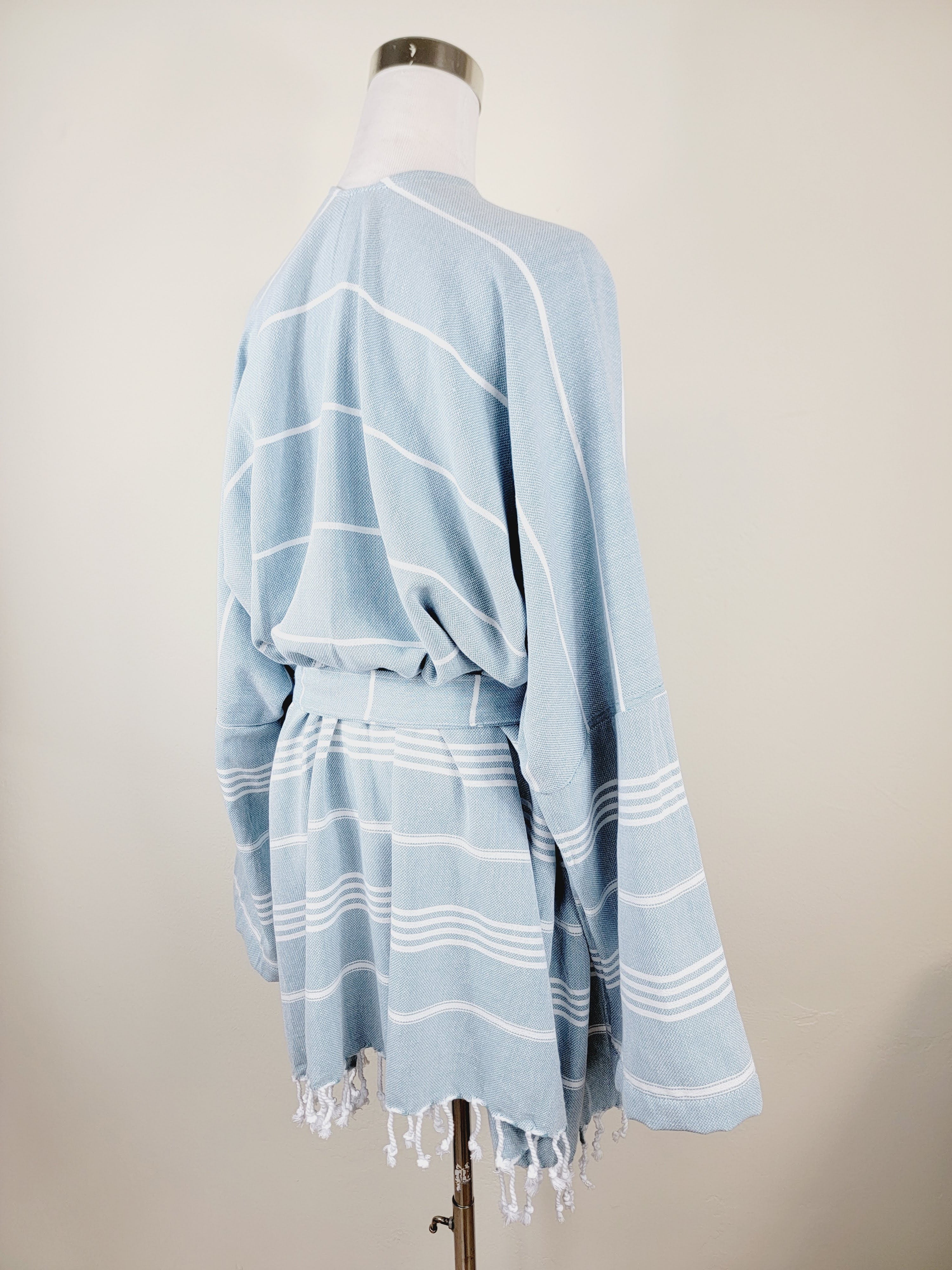 Light blue striped poncho on a mannequin against a plain background