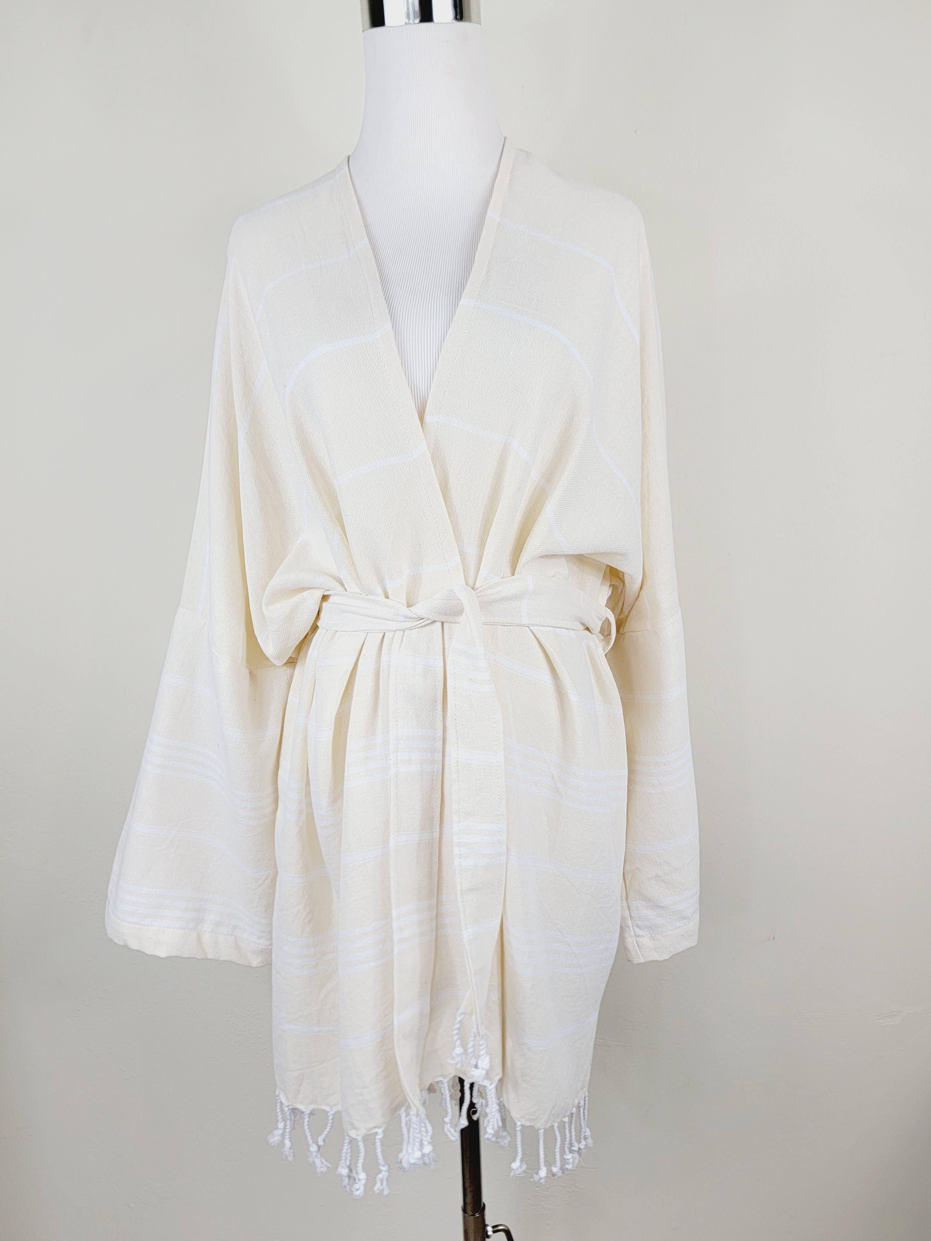 White robe with fringes on a mannequin against a white background