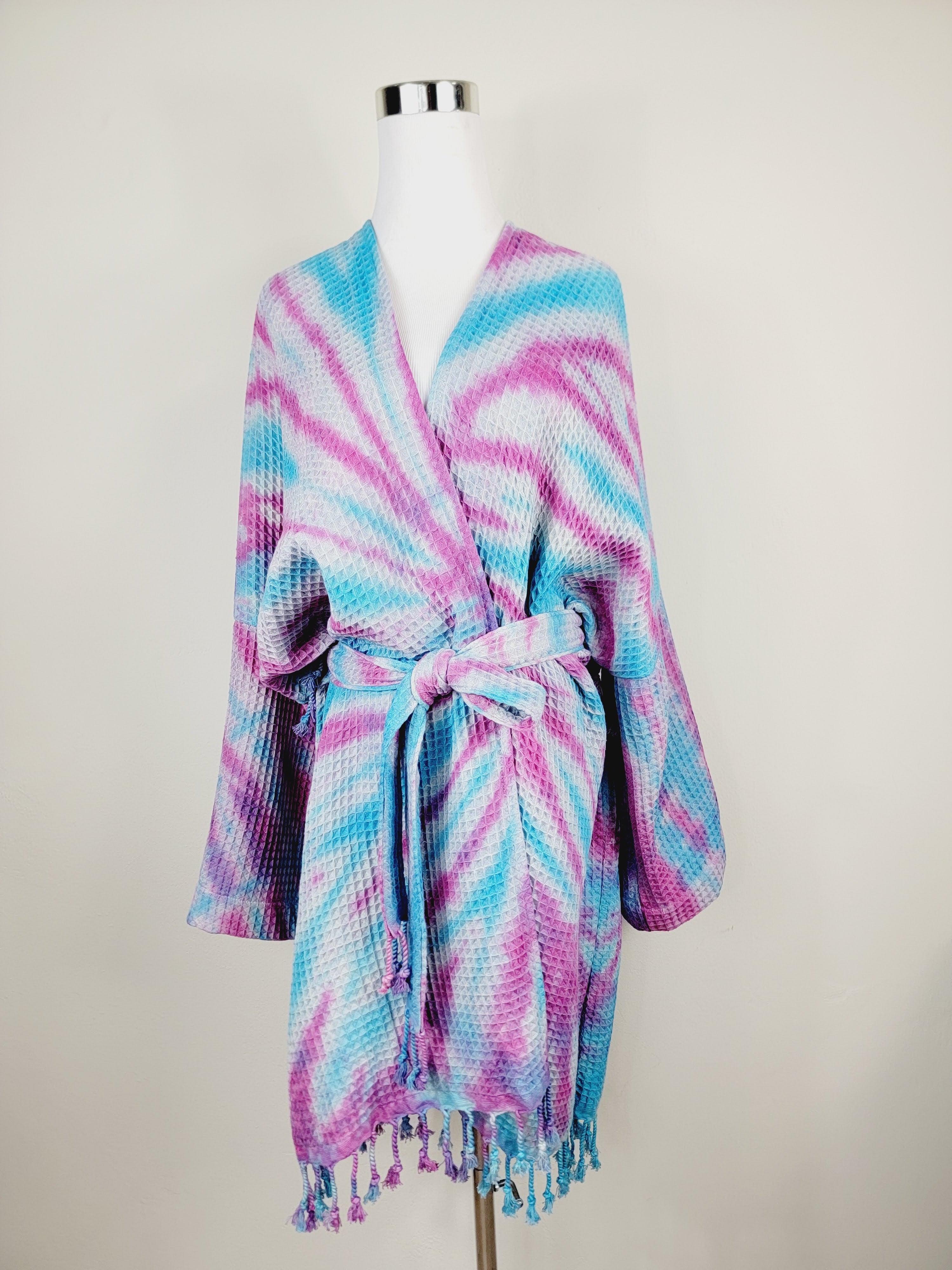 Tie-dye robe with fringes on a mannequin against a plain background