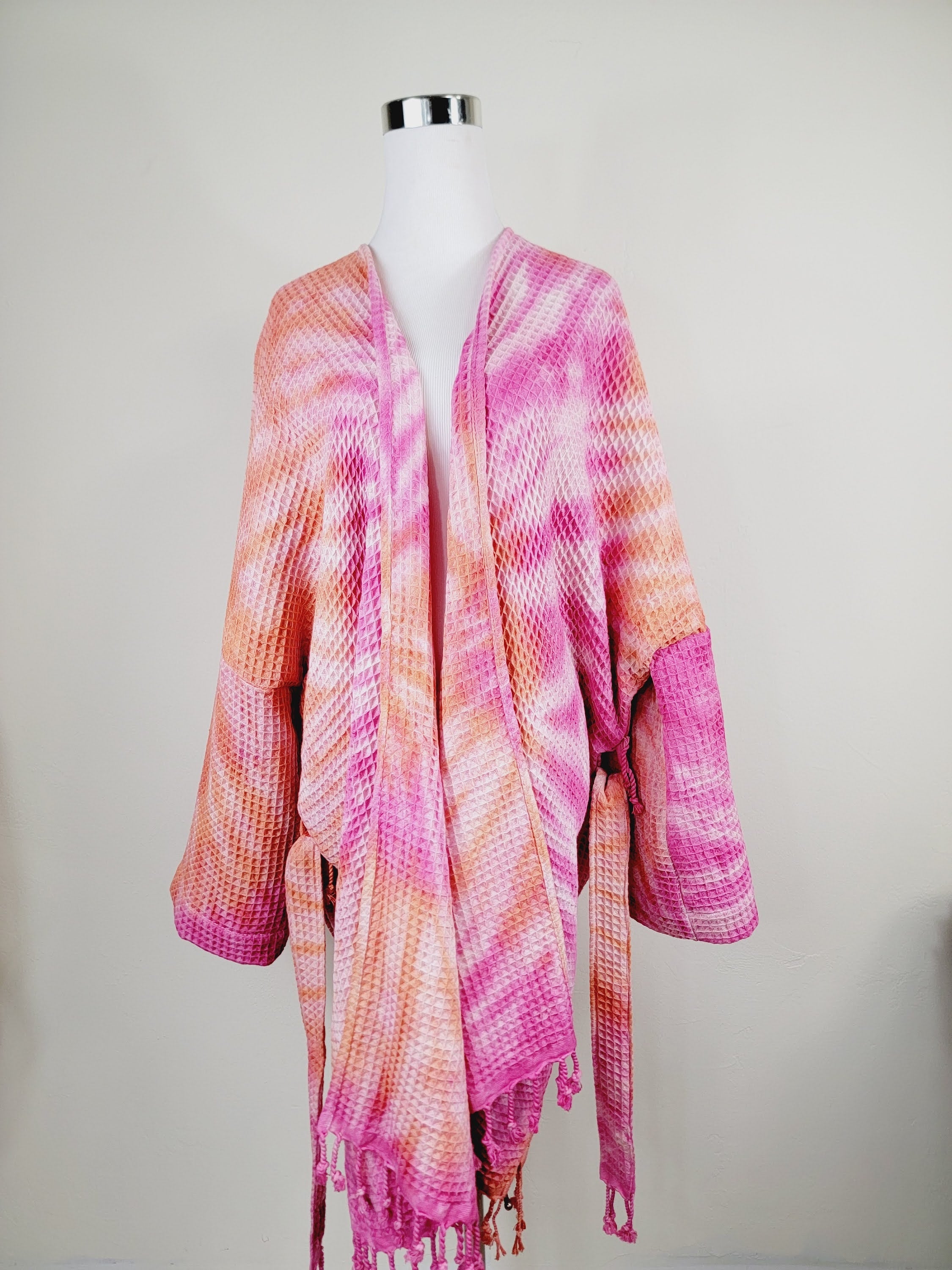 Mannequin wearing a pink and orange patterned scarf on a plain background