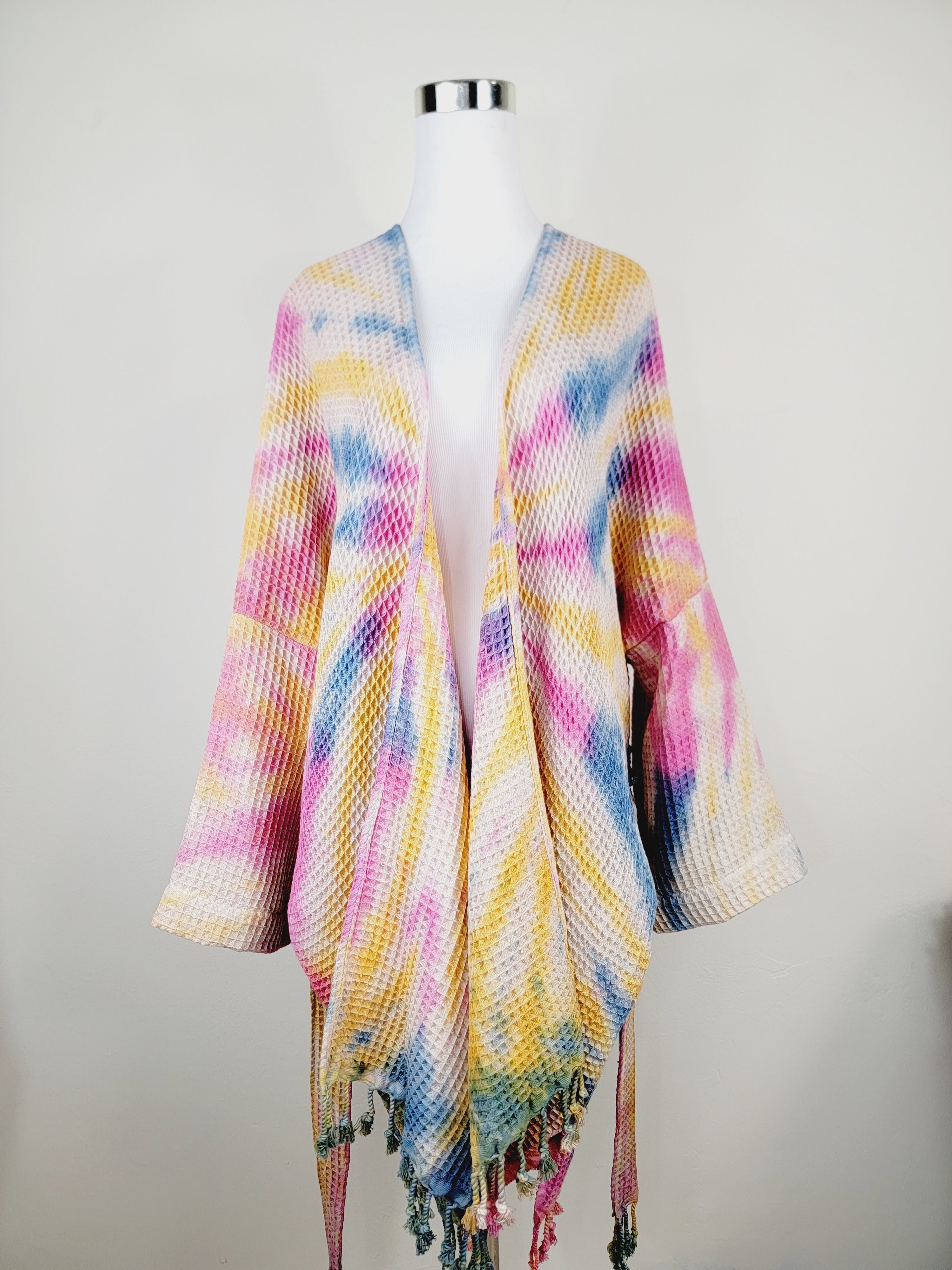 Colorful knitted shawl on a mannequin against a plain background