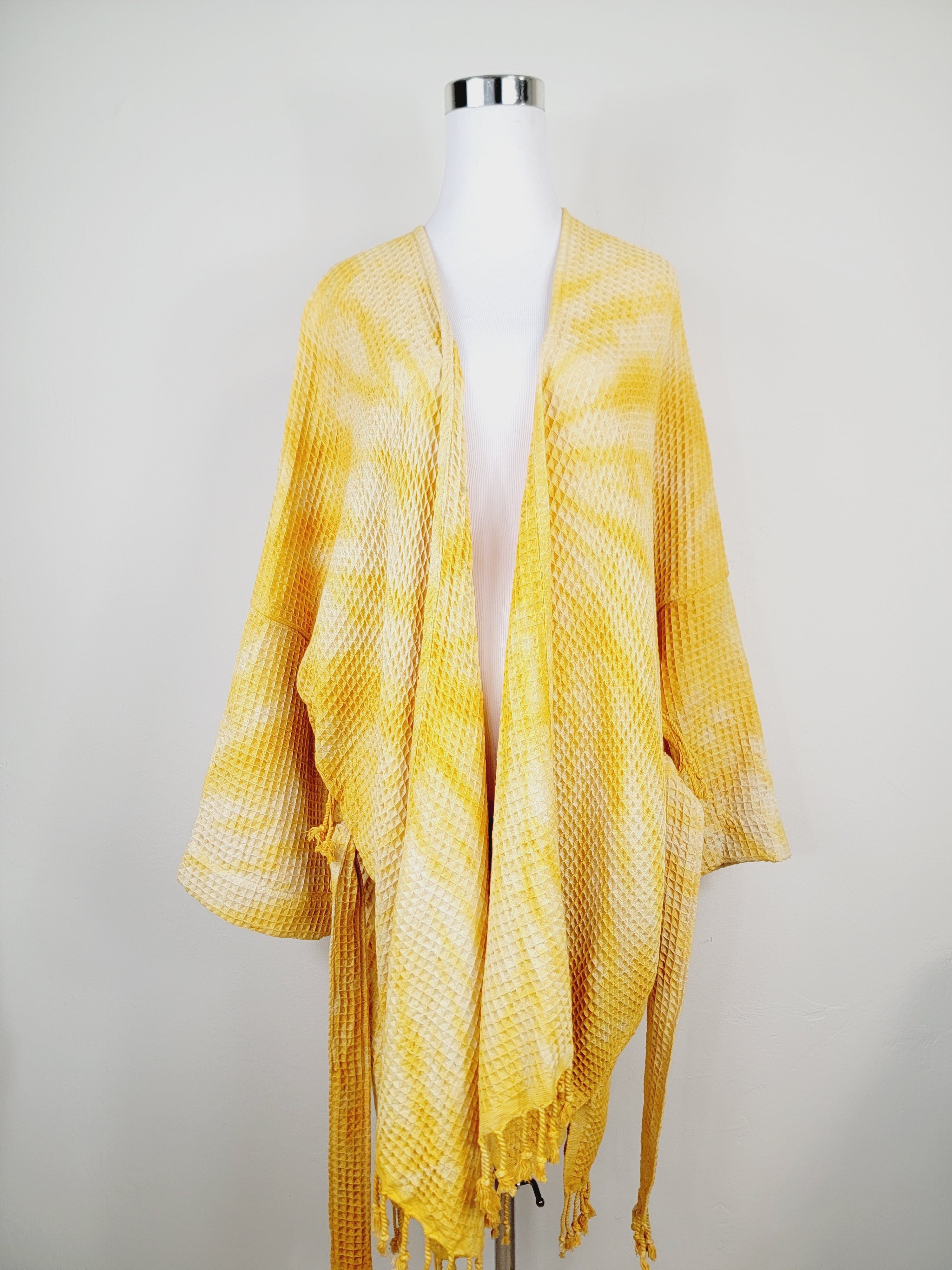 Yellow textured scarf on a mannequin against a plain background