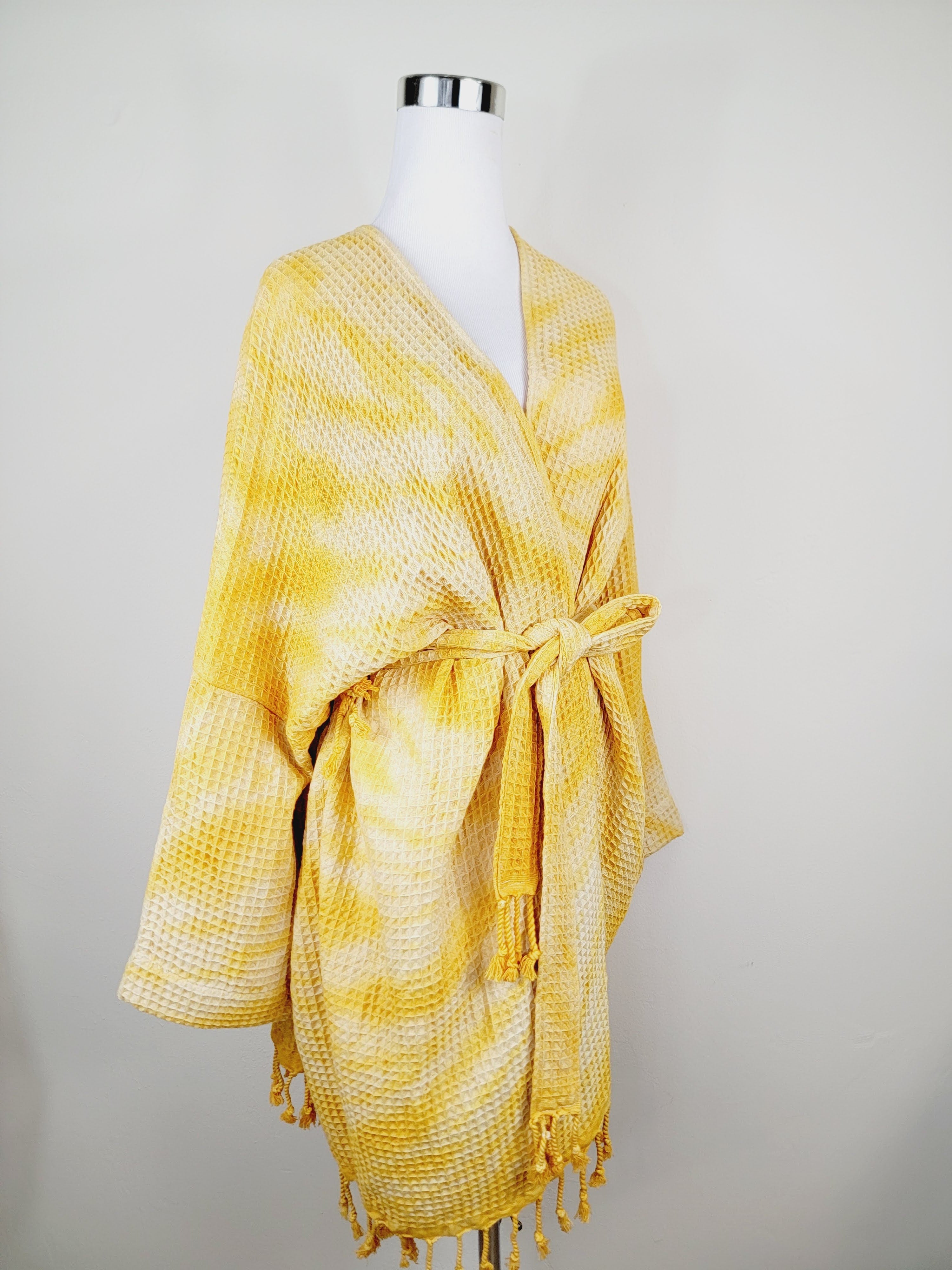 Yellow checkered shawl with fringes on a mannequin against a plain background