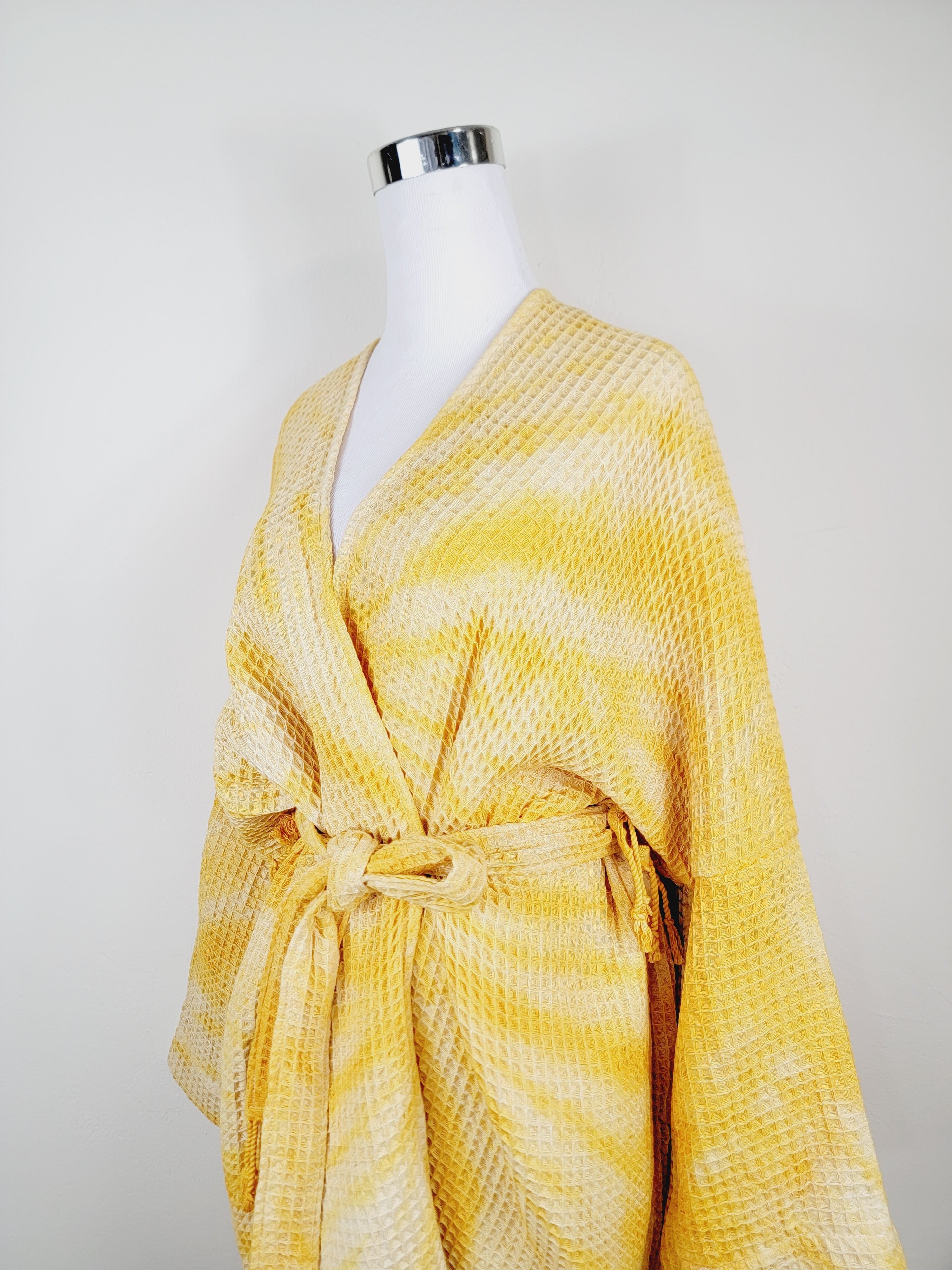 Yellow textured robe on a mannequin against a white background