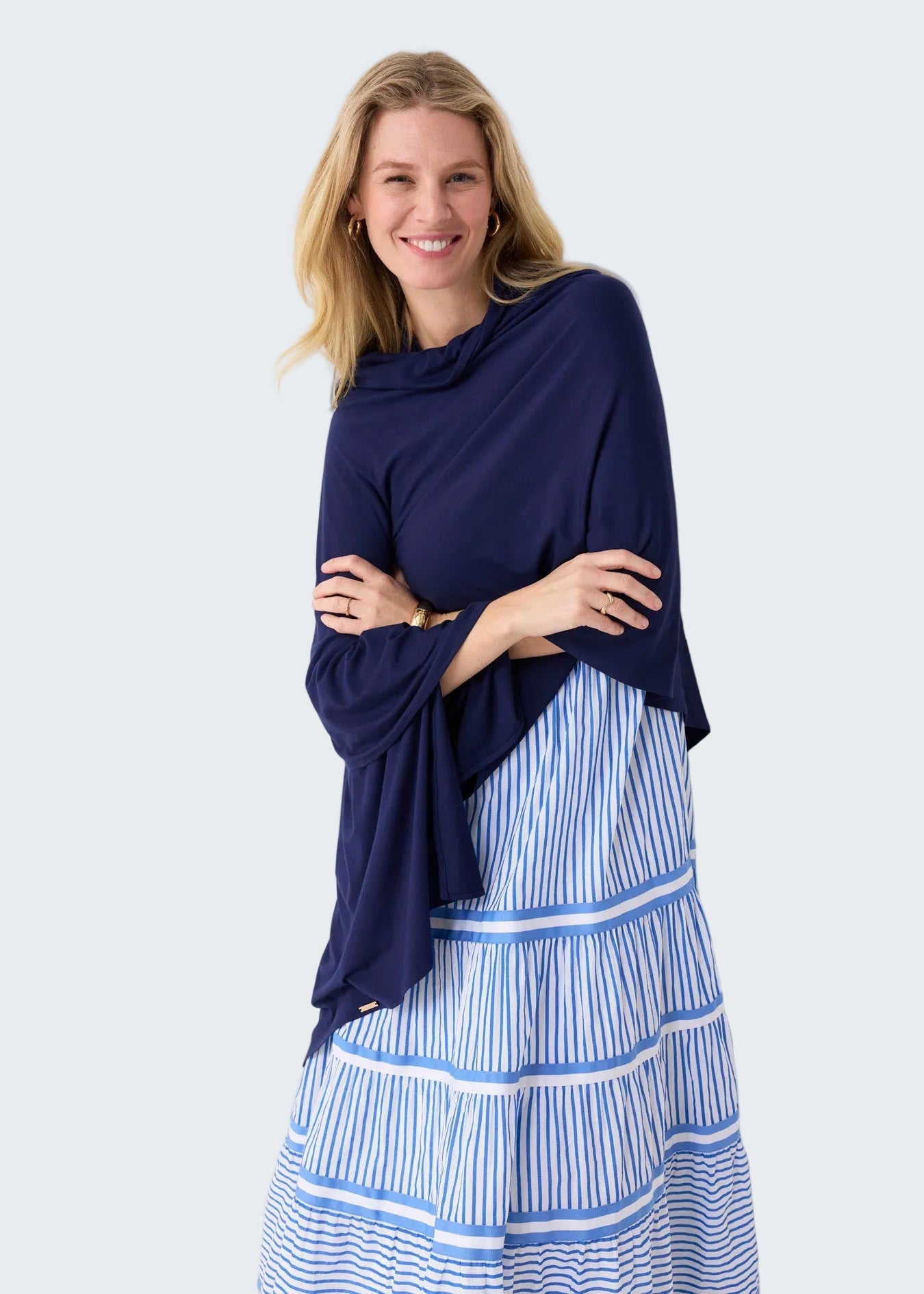 Woman wearing a navy blue top and blue and white striped pants against a white background