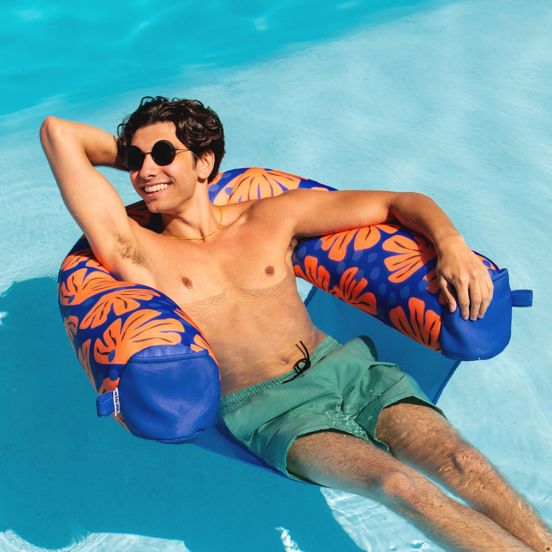 Man lounging on a blue and orange inflatable tube in a pool