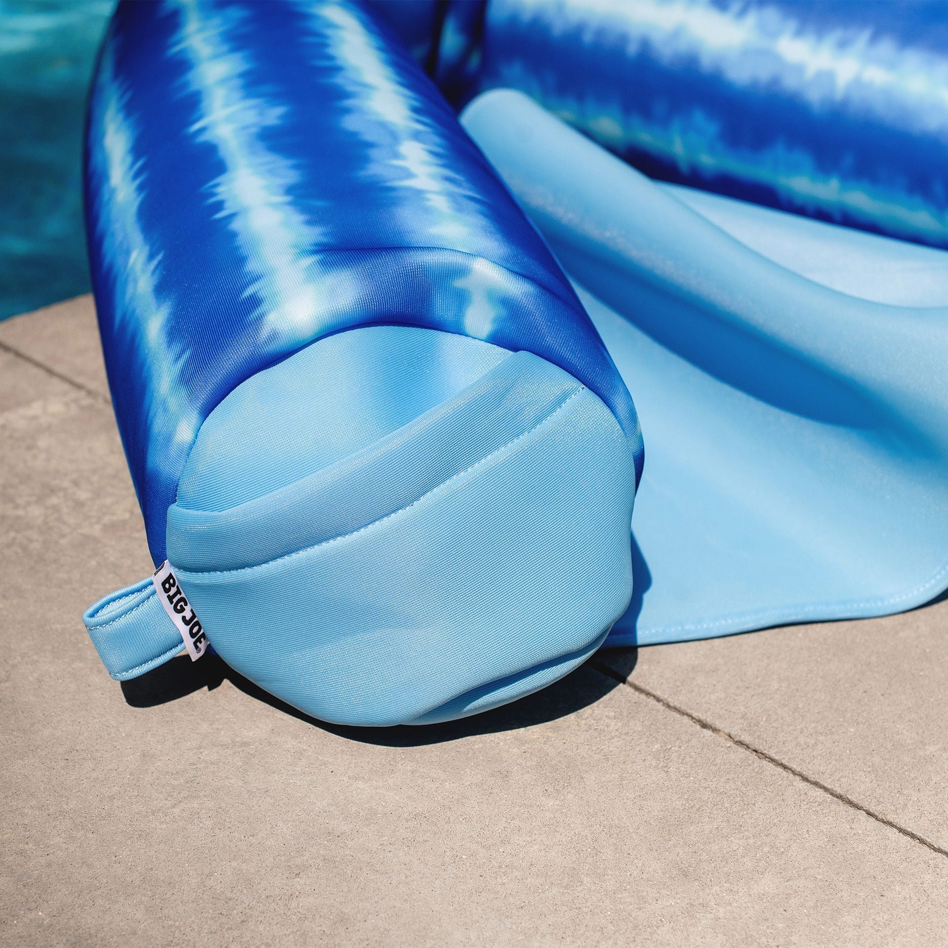 Blue inflatable pool float on a concrete surface near water